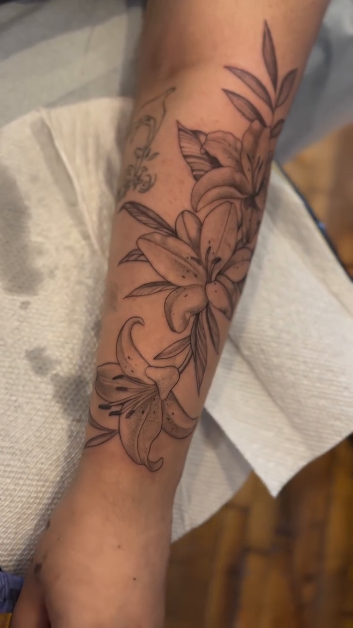 Lily floral arrangement on forearm fine line tattoo on the forearm by High Vibrations