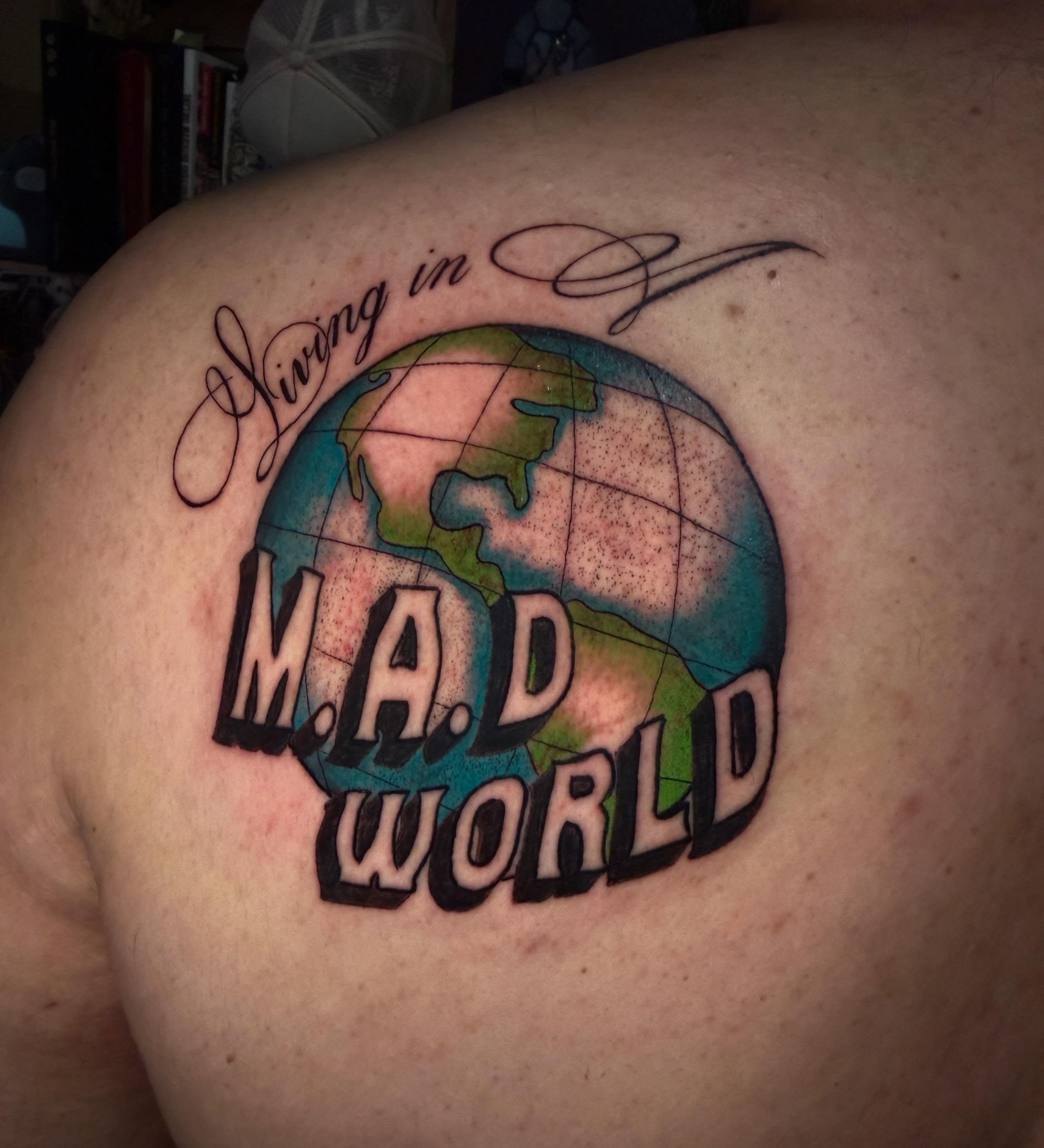 Living in M.A.D World lettering script tattoo on the back by Lydia