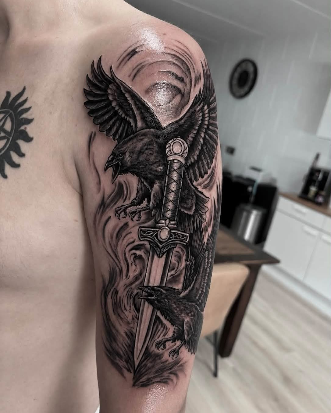 Crow and sword realism tattoo on the upper arm by Léon Huiting