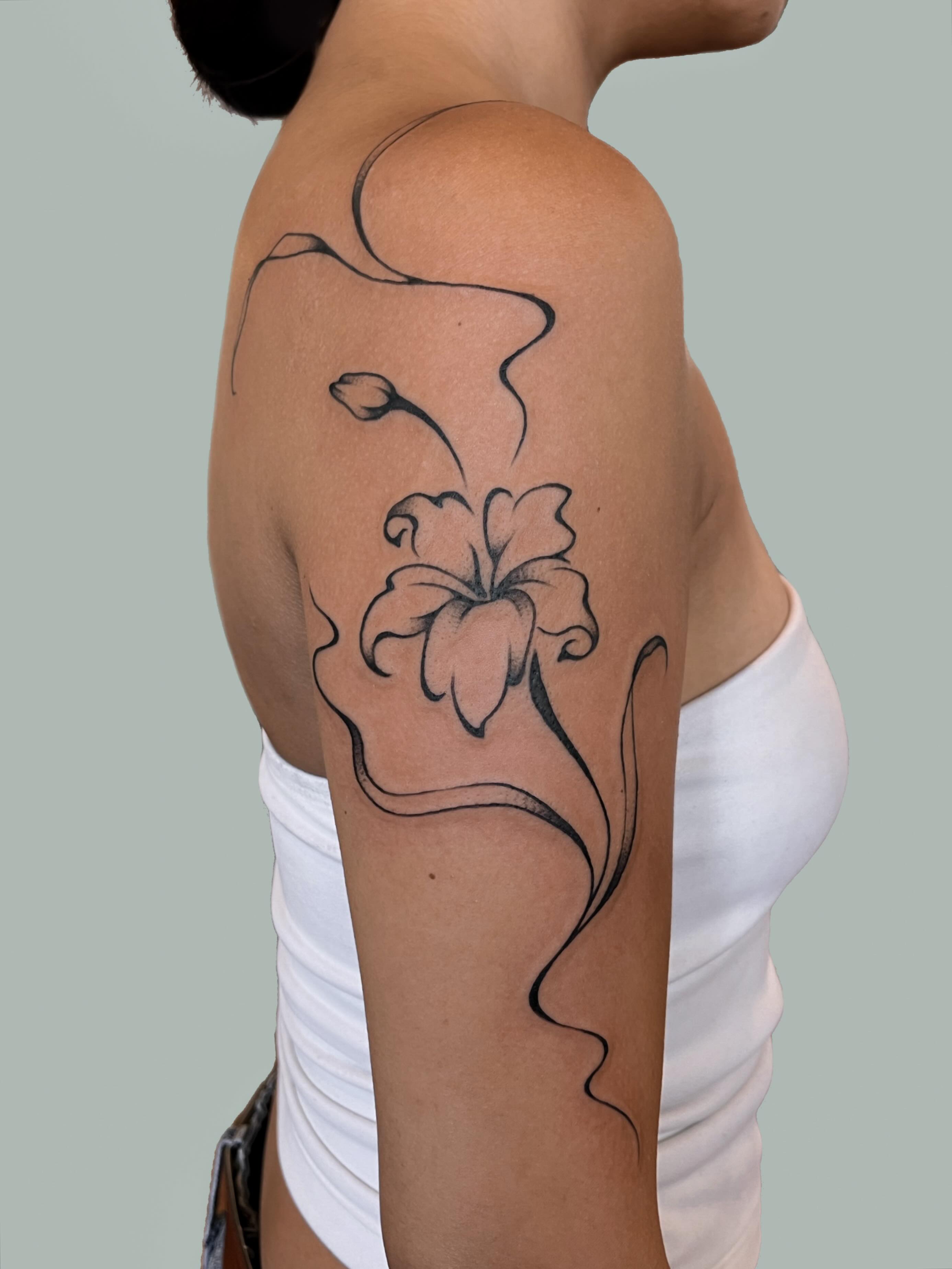 Lily black and grey tattoo on the upper arm by nina