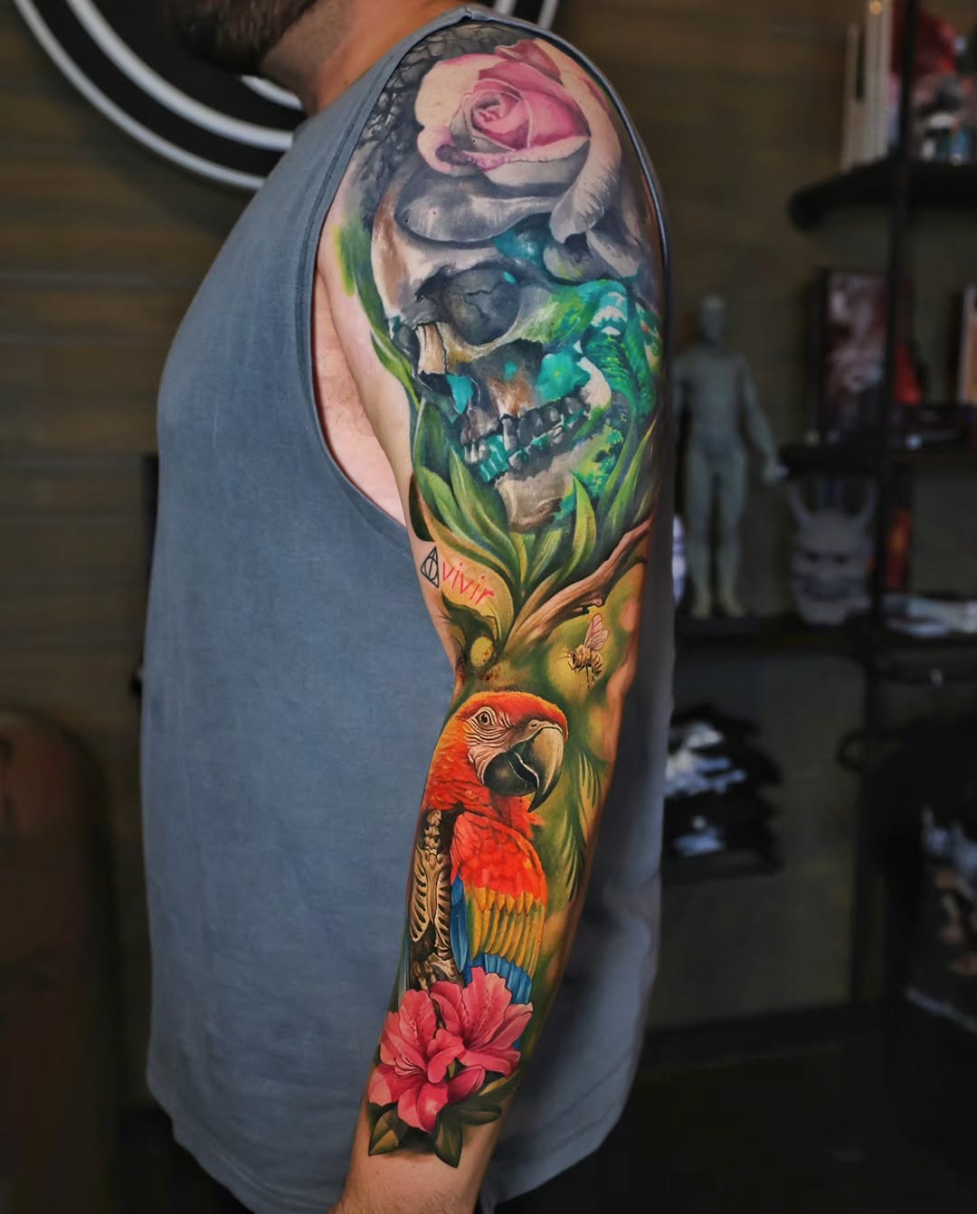 Skull, rose, parrot, and flowers watercolor tattoo on the forearm by Marek Pawlik