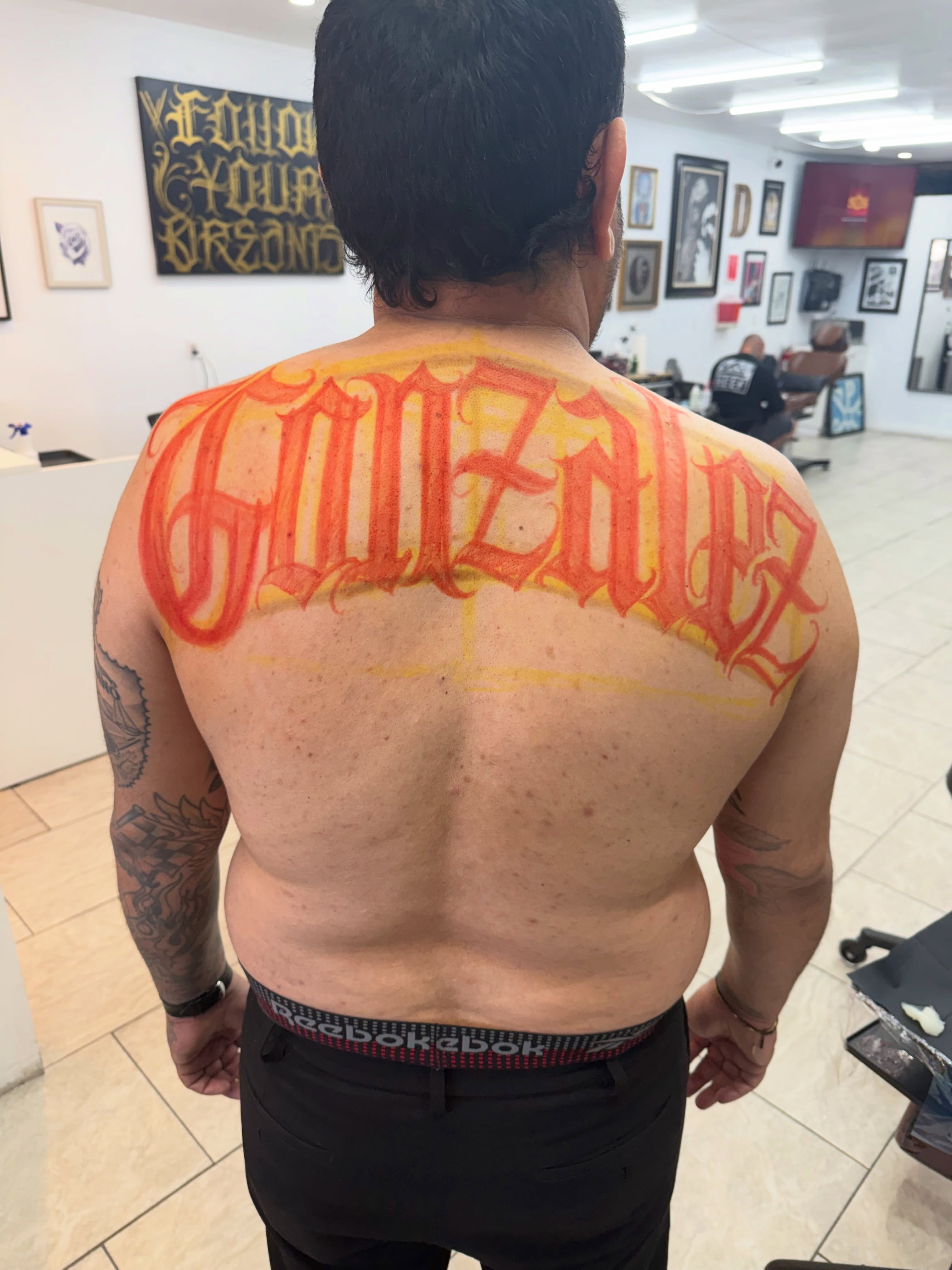 GonzΓ‘lez lettering script tattoo on the back by Daniel Lopez Tattoos