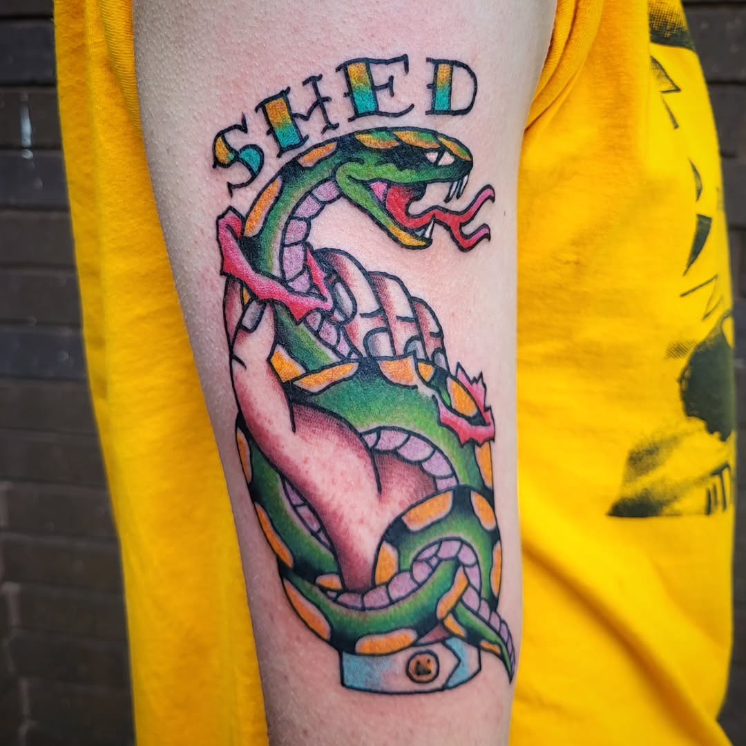Snake shedding skin over hand American traditional tattoo on the forearm by Sloan Smith