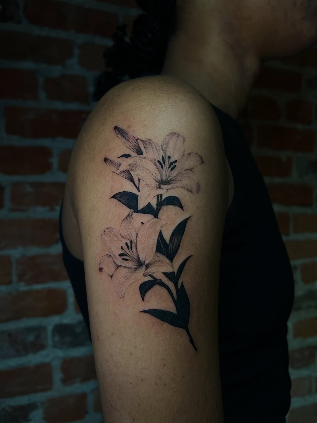 Lilies fine line tattoo on the thigh by Uncomfy Comfort Tattoos LLC