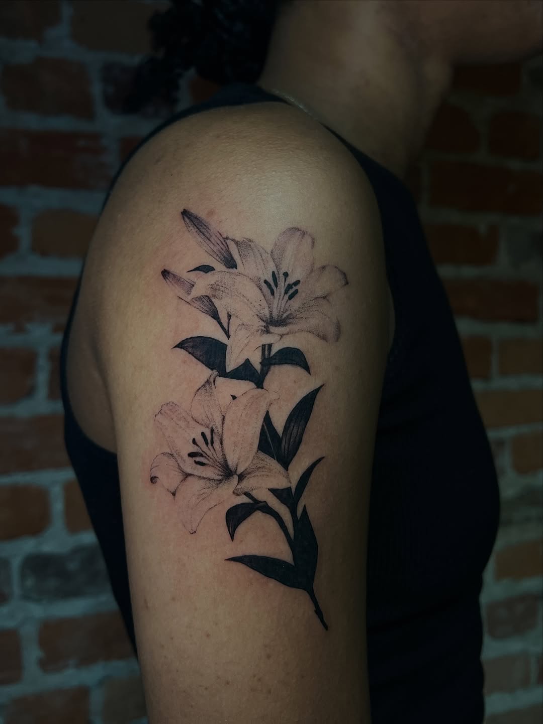 Lilies fine line tattoo on the shoulder by Uncomfy Comfort Tattoos LLC