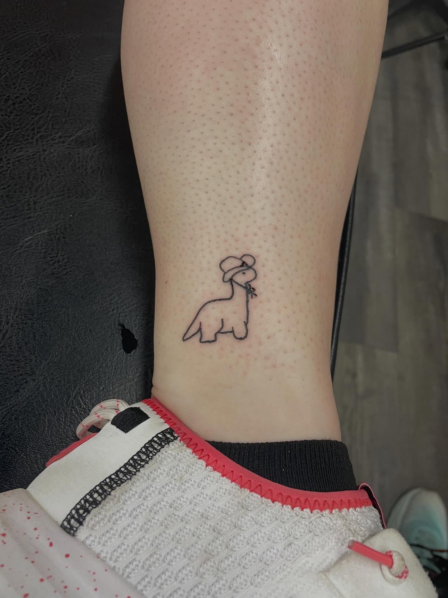 Dinosaur wearing hat dotwork tattoo on the calf by Yaya tattoo
