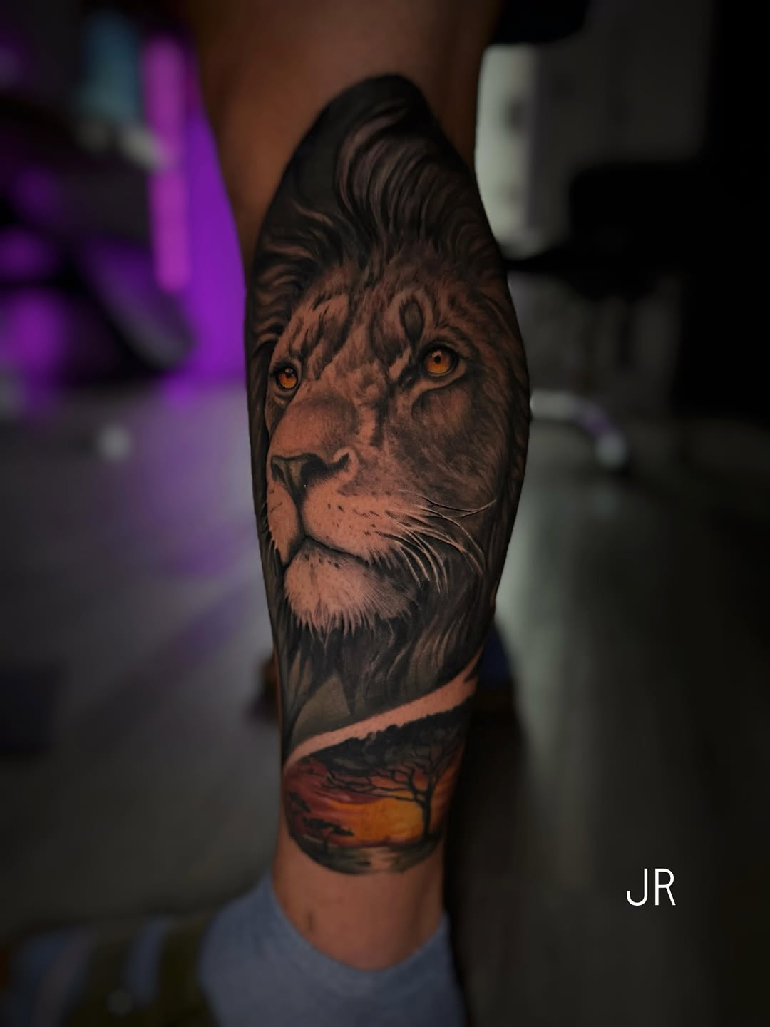 Lion portrait with sunset landscape realism tattoo on the forearm by Juan Russo