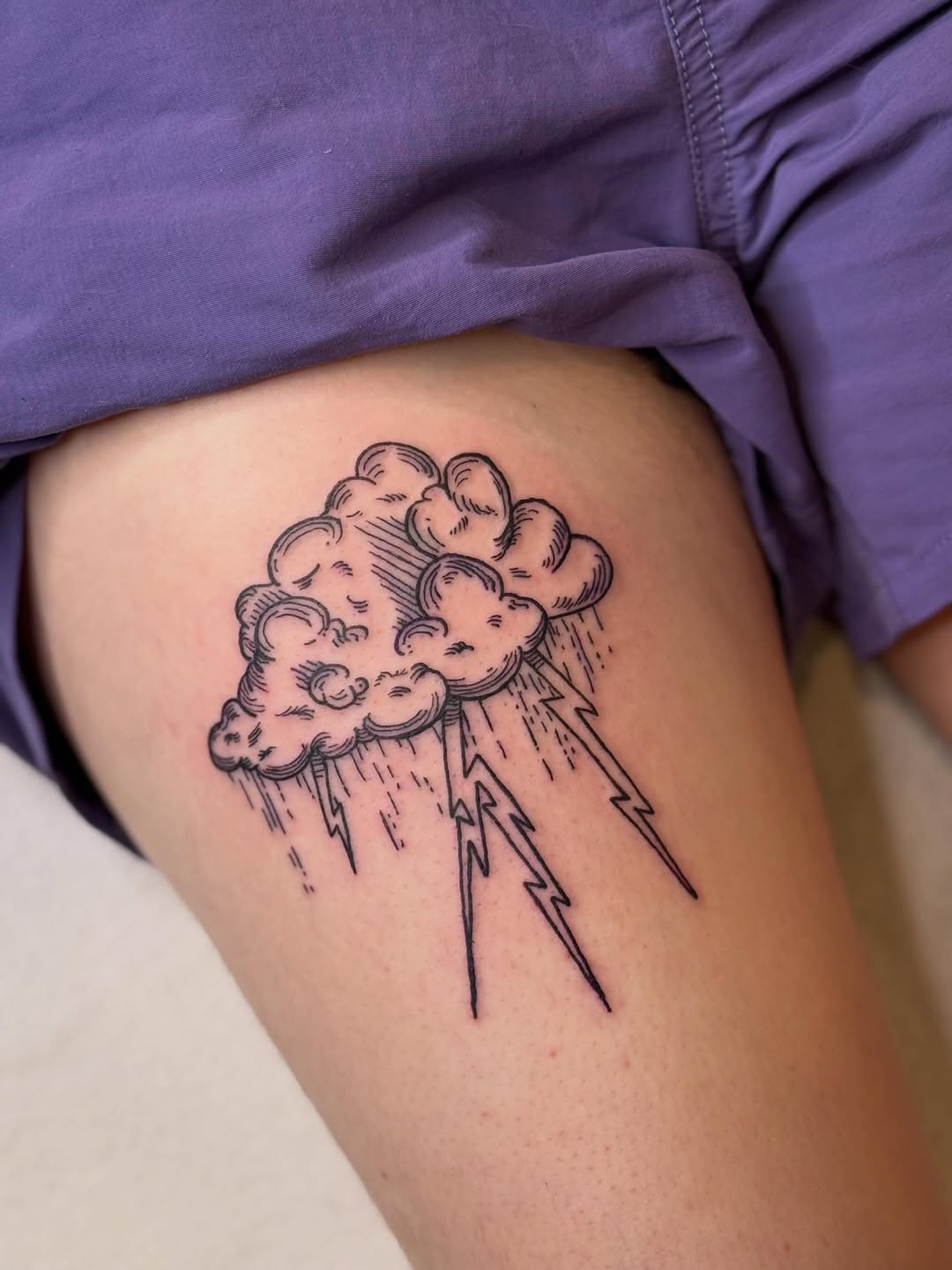 Cloud with lightning and rain fine line tattoo on the thigh by Eric Guntor, Philadelphia, Pennsylvania