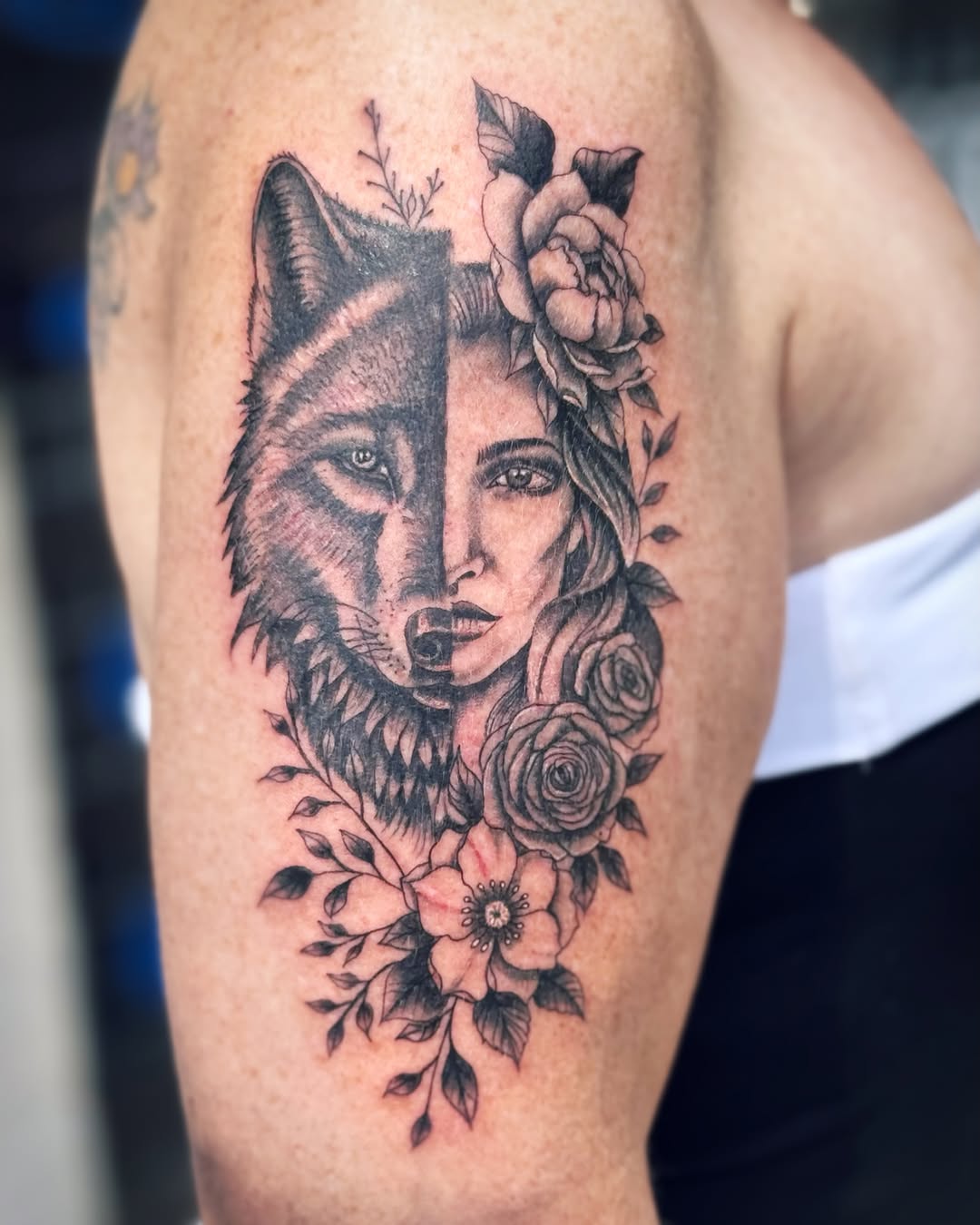 Wolf and woman portrait with flowers realism tattoo on the upper arm by Kate