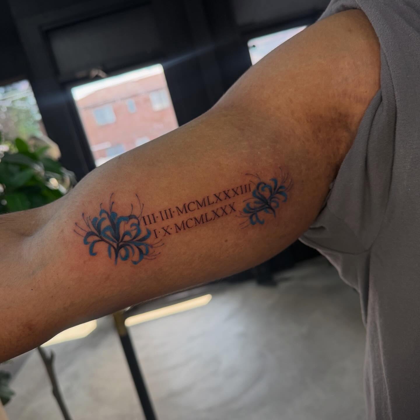 Roman numerals with floral accents fine line tattoo on the forearm by Angela Azure