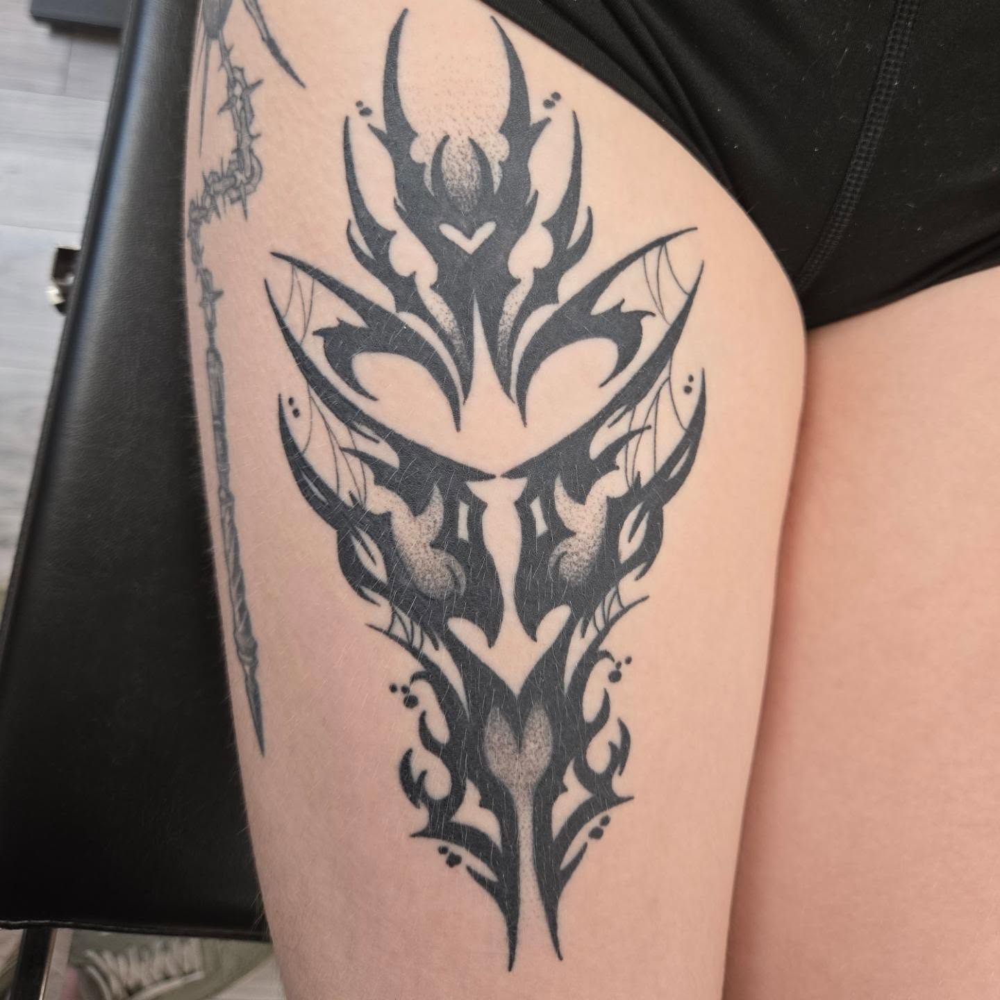 Mask tribal tattoo on the thigh by Kylie