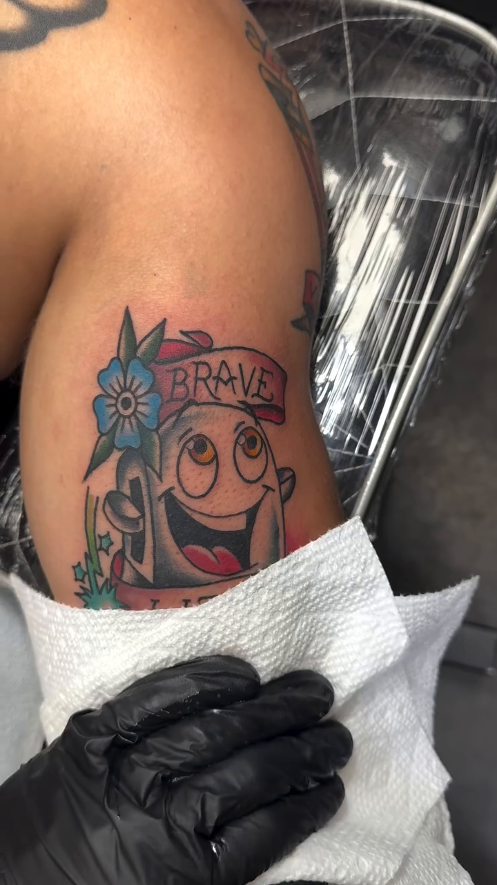 Cartoon bath bomb with flowers minimalist tattoo on the upper arm by Michael Roehrich (MEECH!)