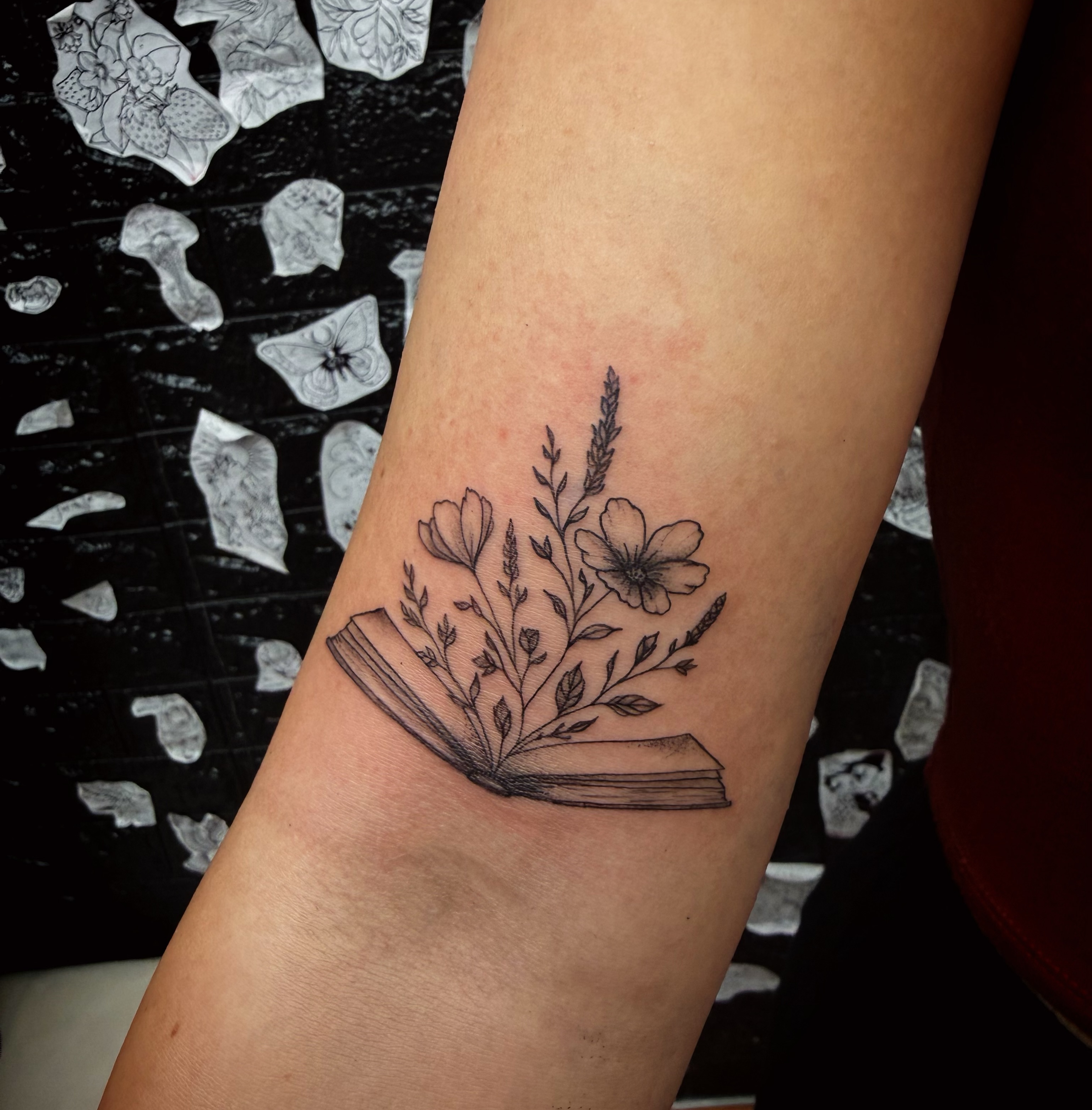 Book with floral arrangement black and grey tattoo on the forearm by Kraken ink Tattoo, San Francisco, California