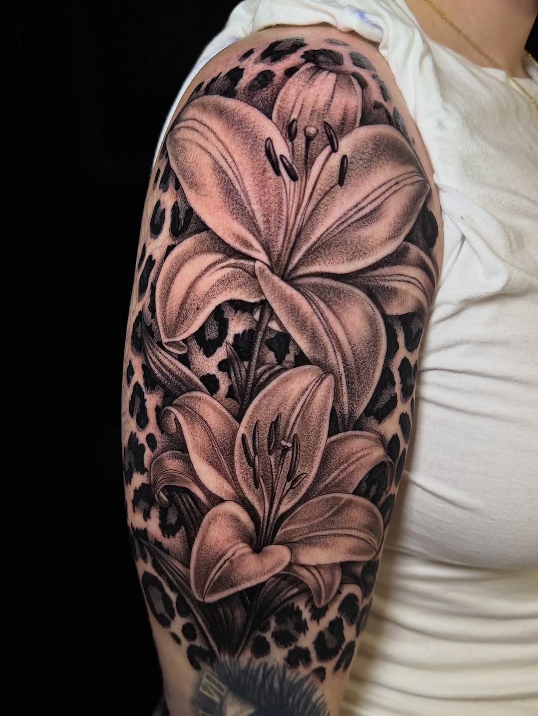 Lilies and leopard print fine line tattoo on the upper arm by Eduardo Chaparro