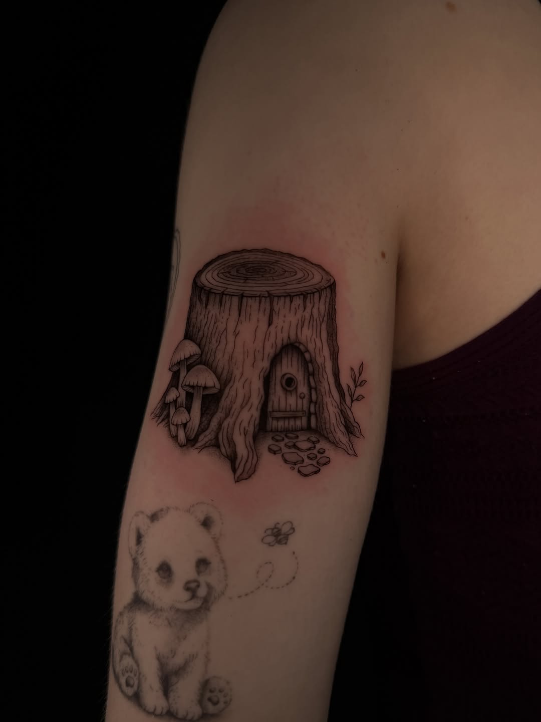 Tree stump fairy house with mushrooms fine line tattoo on the forearm by Marianne