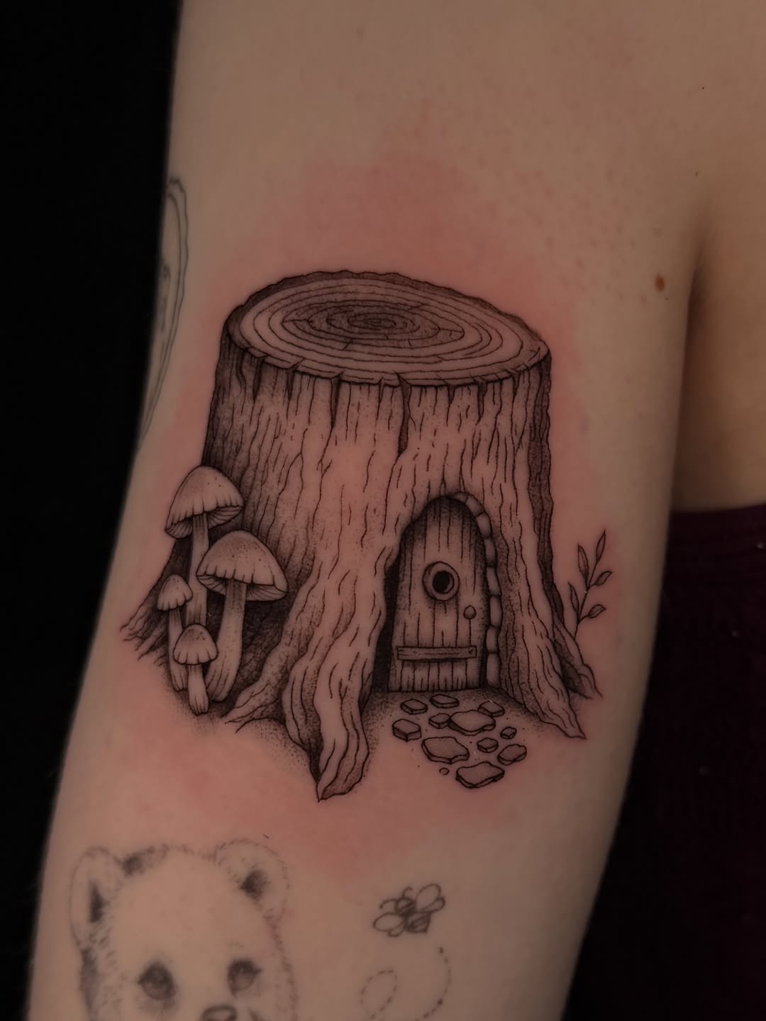 Tree stump house with mushrooms fine line tattoo on the forearm by Marianne