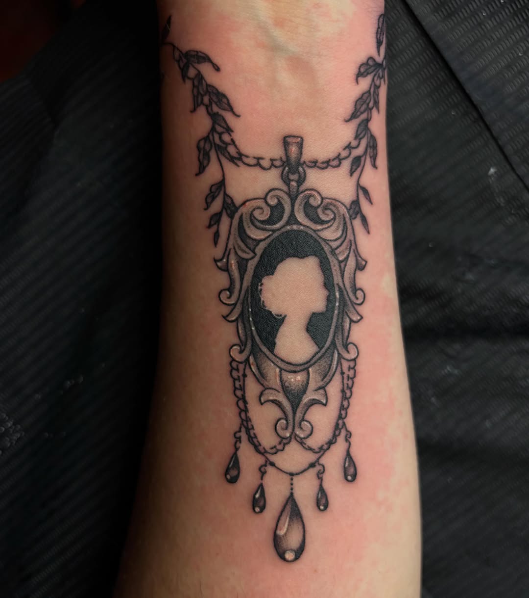 Cameo pendant with leaves ornamental tattoo on the forearm by destany aguilera, Davenport, Iowa