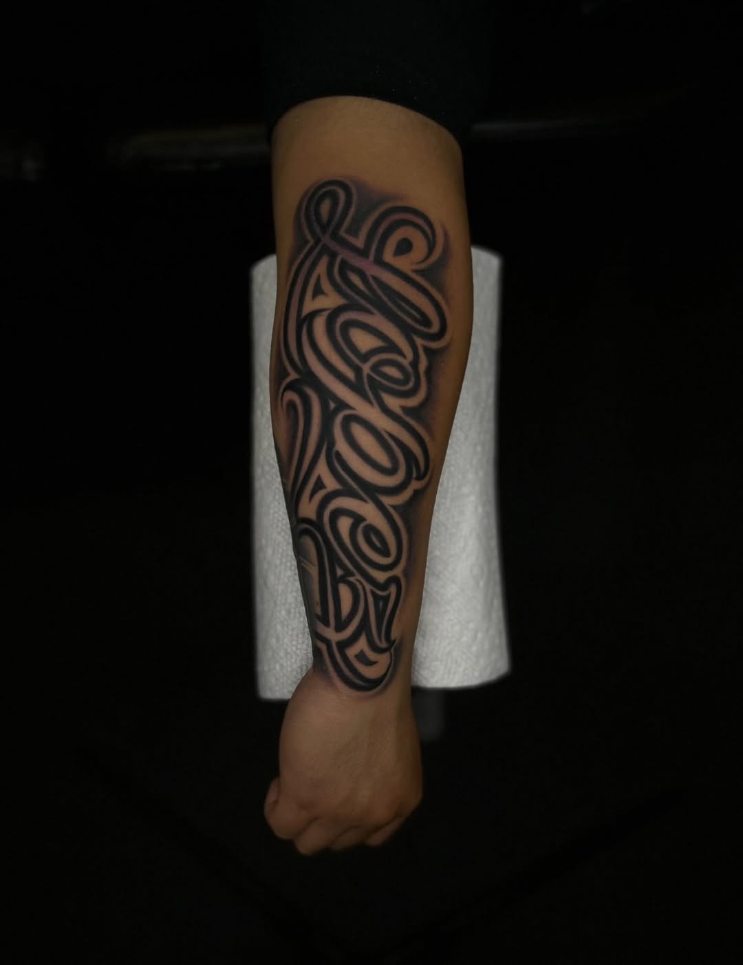 Script lettering Chicano tattoo on the forearm by Tattoo Artist