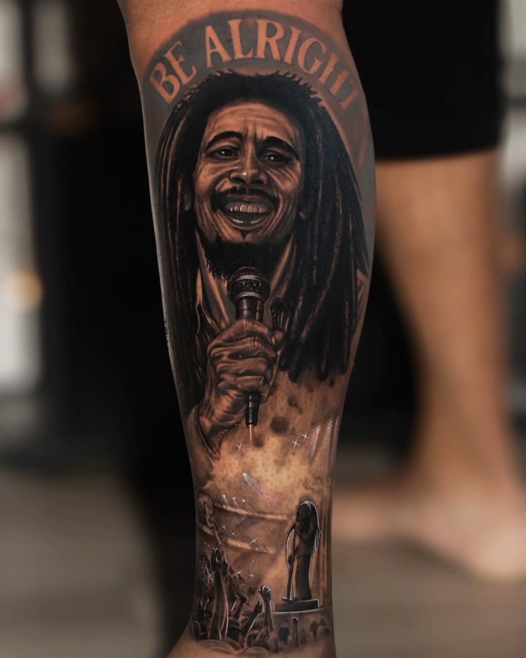 Bob Marley portrait with concert scene realism tattoo on the forearm by Baxtertattoo