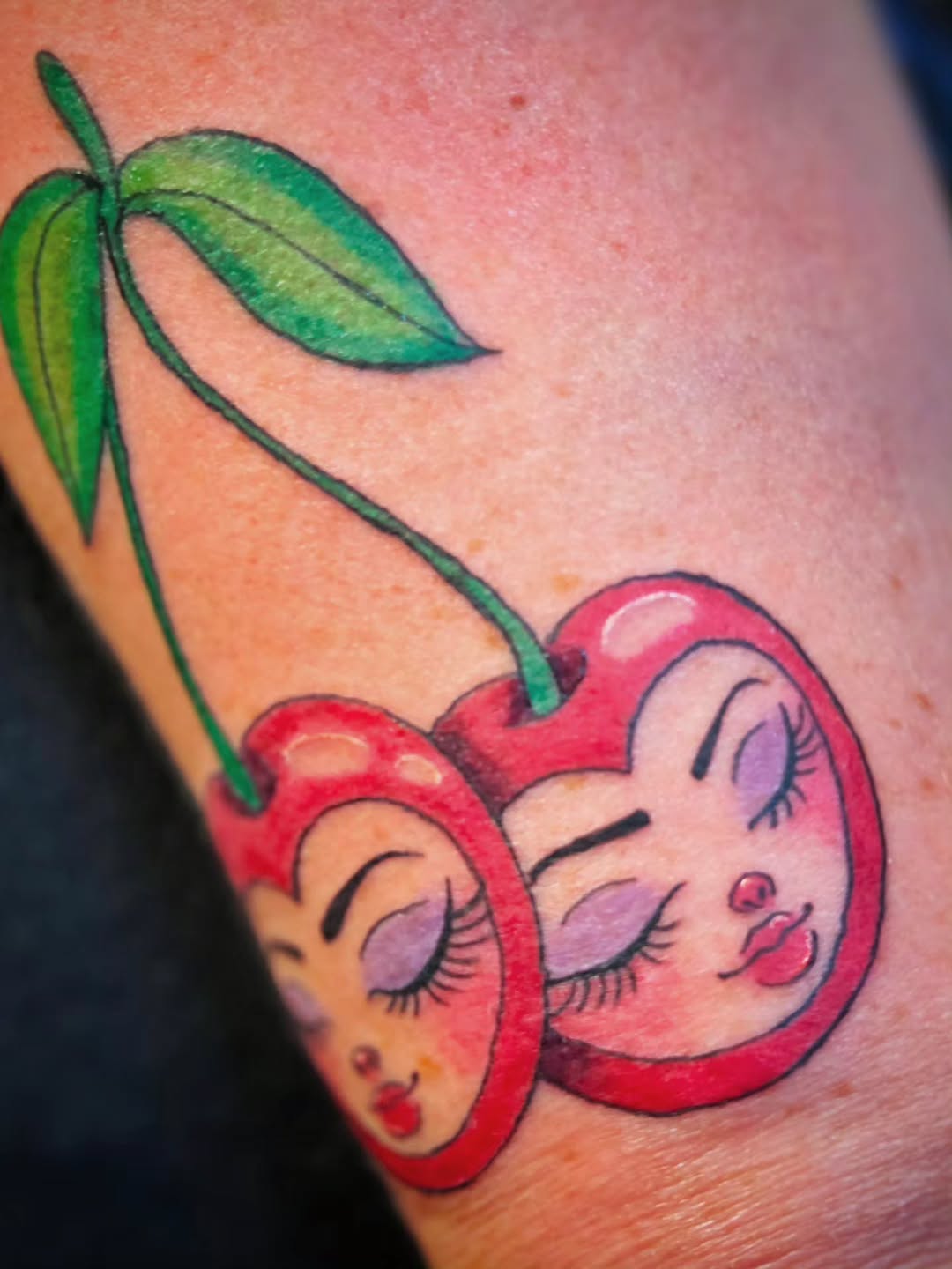 Cherries with faces neo-traditional tattoo on the upper arm by Jam ⚡️🐉🖤