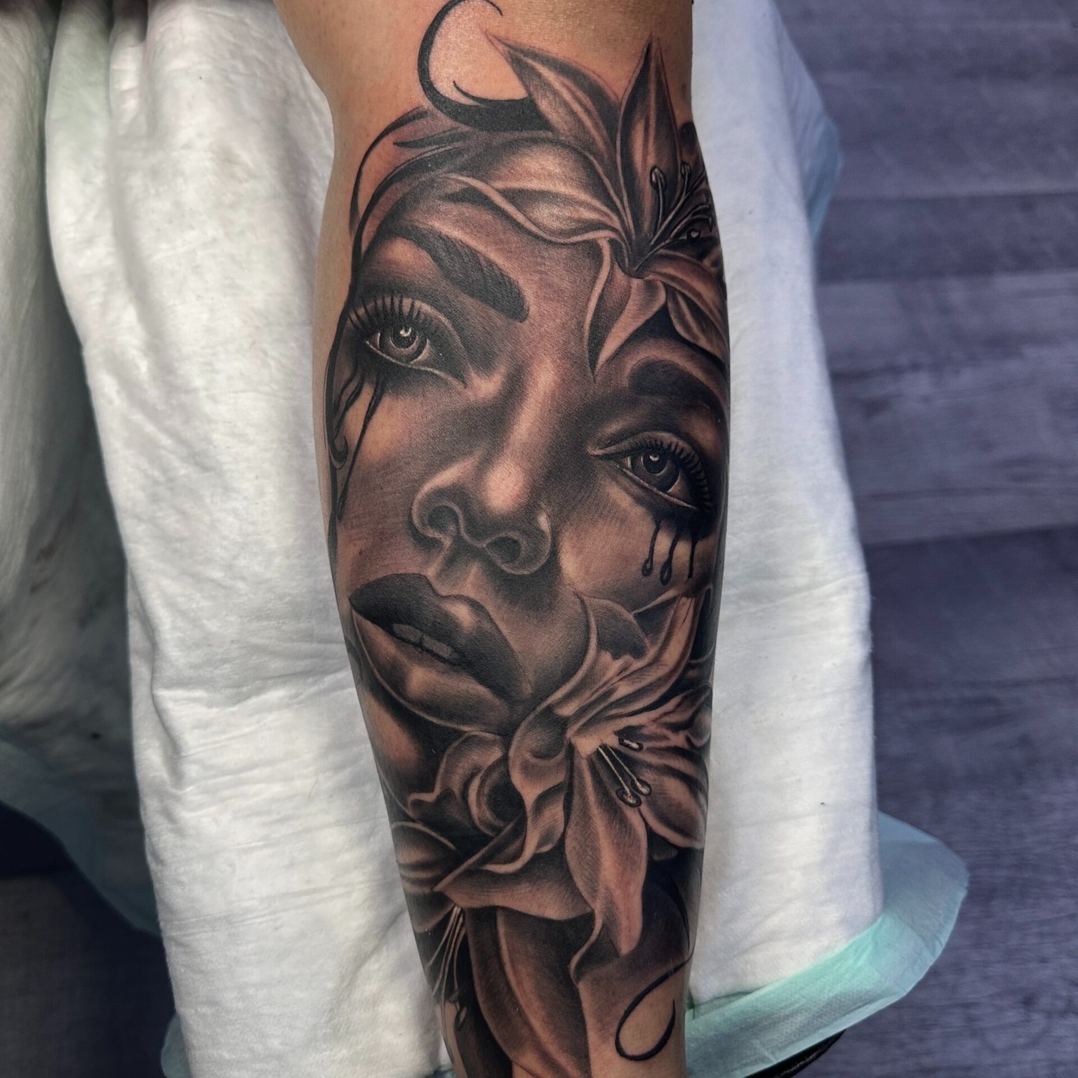 Woman's face with lily realism tattoo on the forearm by jersey ink tattoos, Elizabeth, New Jersey
