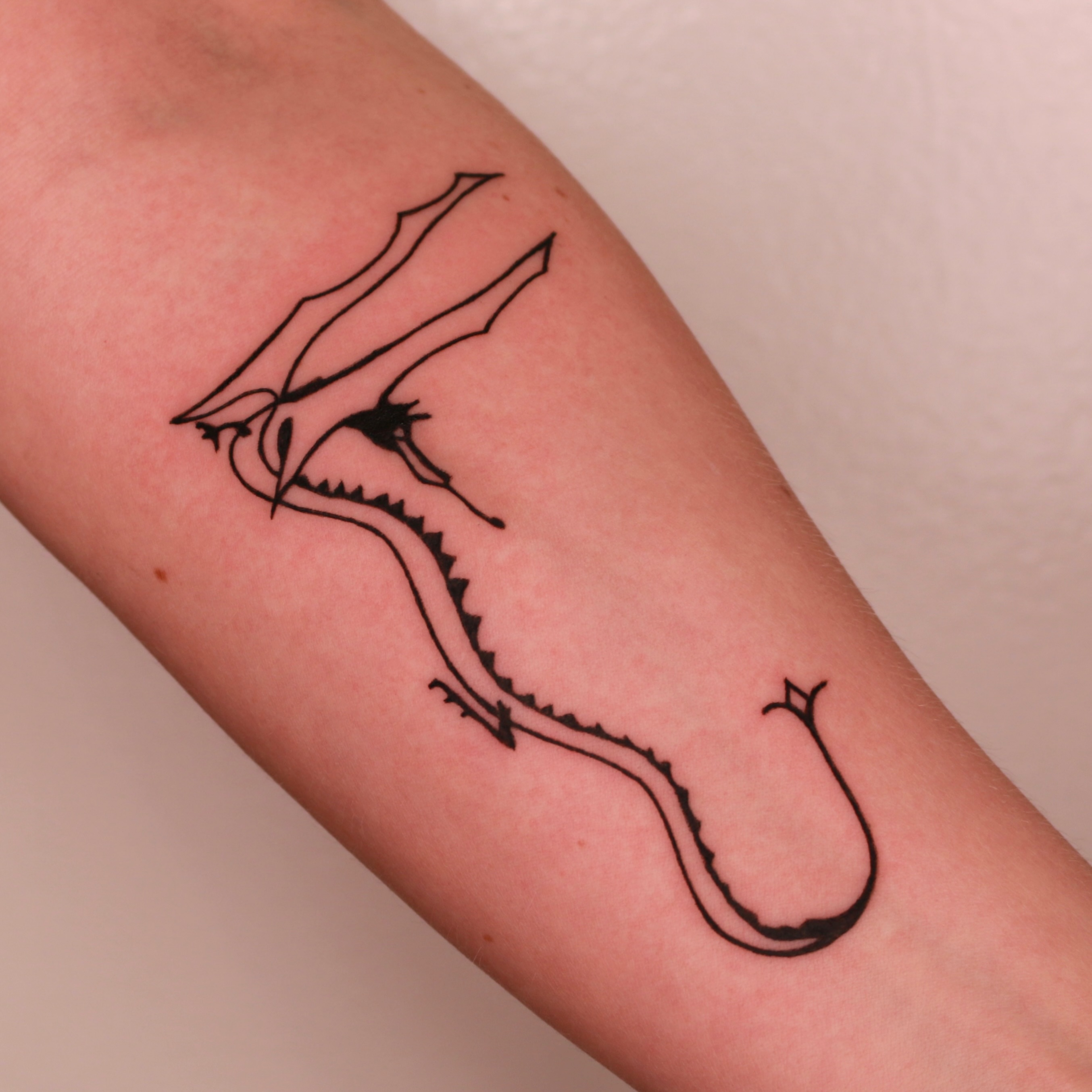 Dragon minimalist tattoo on the forearm by Mike