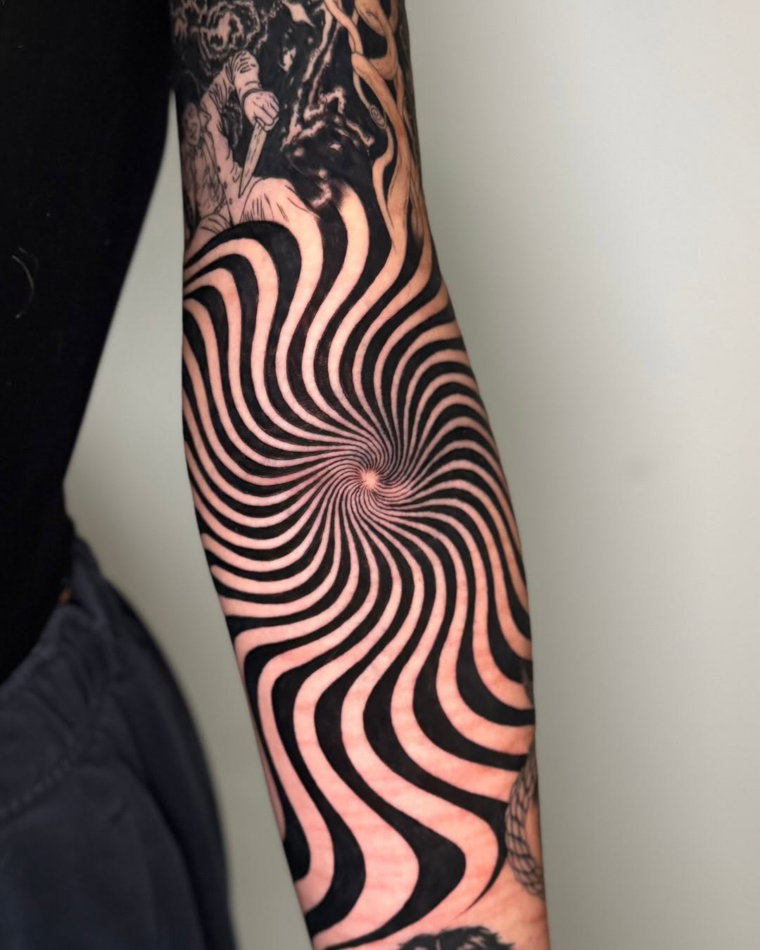 Hypnotic spiral with figures surrealism tattoo on the forearm by Erin Blaney