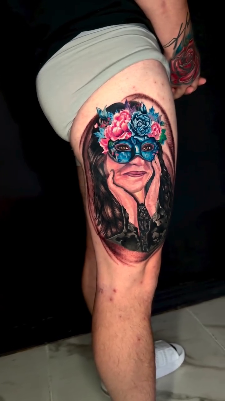 Woman with floral mask surrealism tattoo on the thigh by Goga