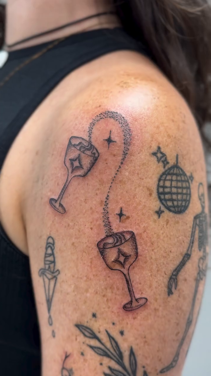 Cosmic cocktail glasses and celestial elements minimalist tattoo on the shoulder by 𝕽𝖆𝖈𝖍𝖊𝖑 𝕽𝖆𝖉𝖎𝖈𝖆𝖑 Queens Tattooer