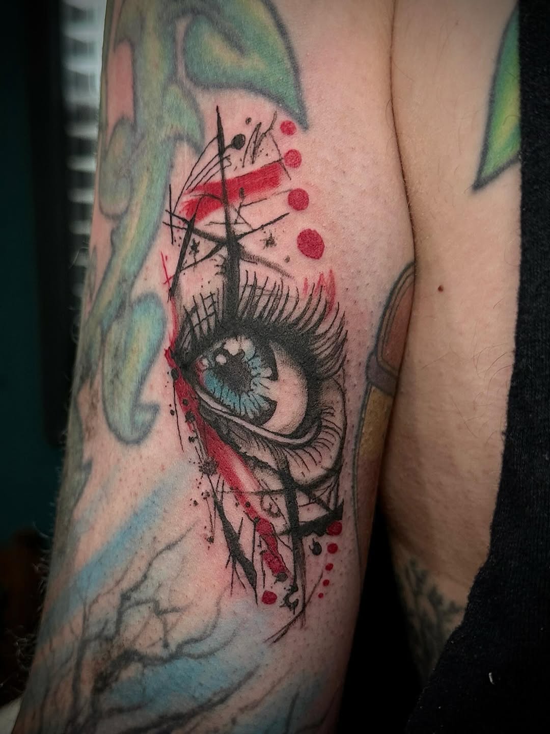 Abstract eye with red accents watercolor tattoo on the forearm by Mika'la Berry