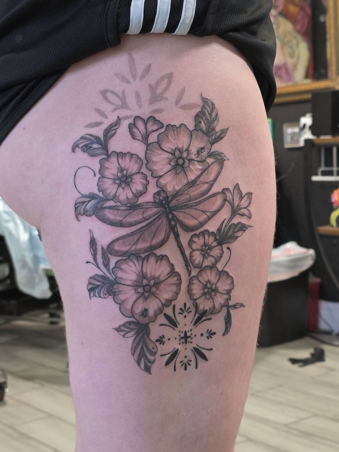 Dragonfly and flowers black and grey tattoo on the thigh by Casey Jo