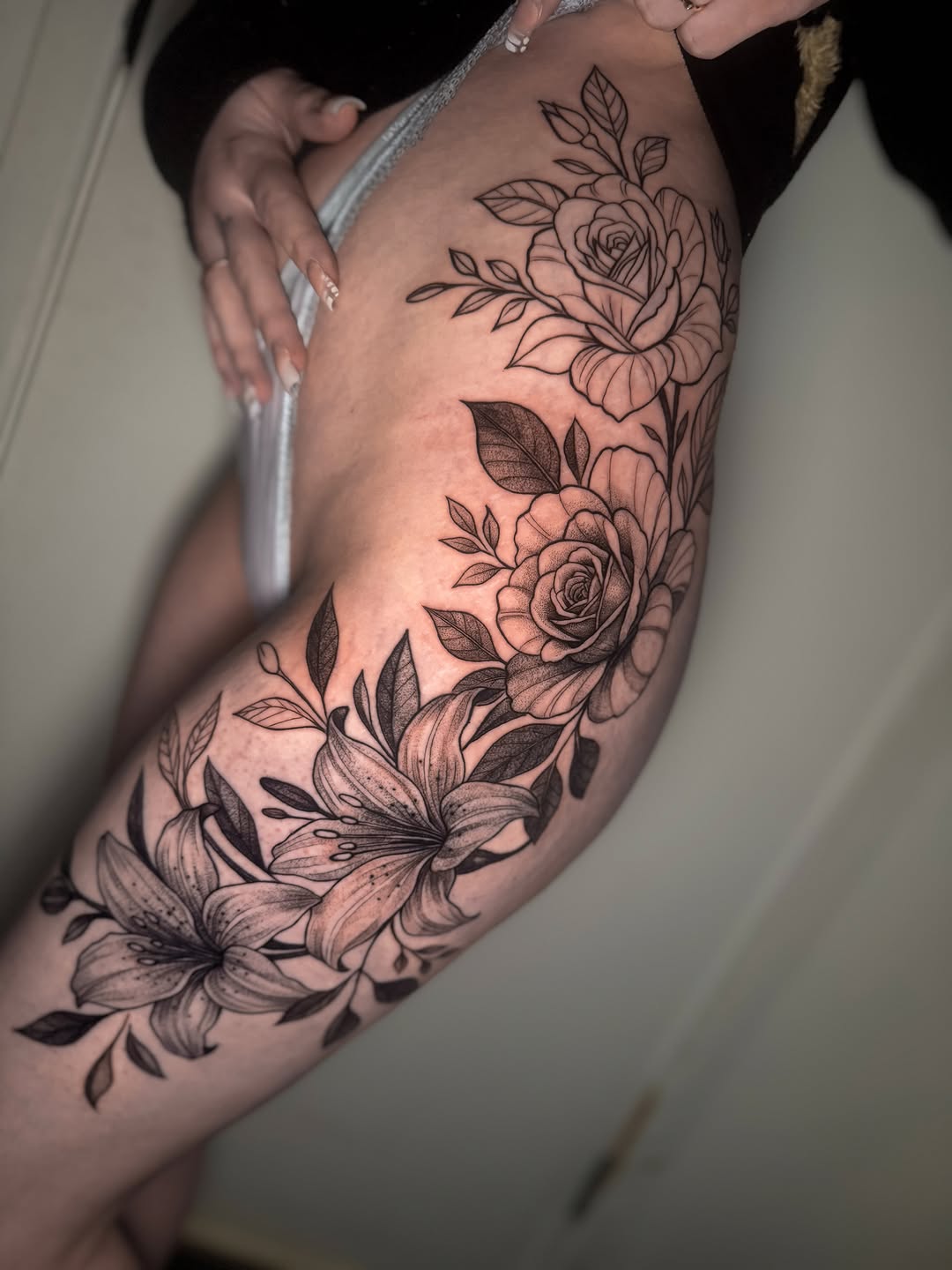 Roses and lilies fine line tattoo on the thigh by Montreal Tattoo Artist