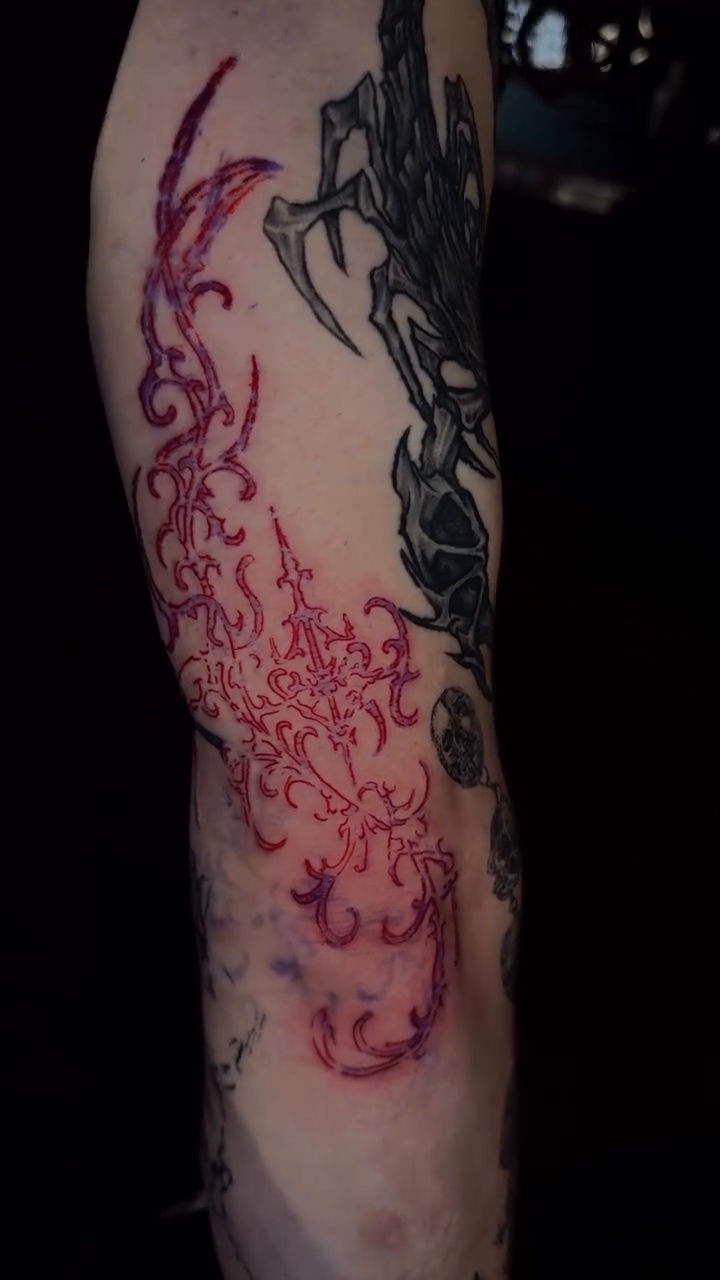 Red flame-like motif on arm cyber sigilism tattoo on the forearm by Seattle Cybersigilism Tattoo Horror