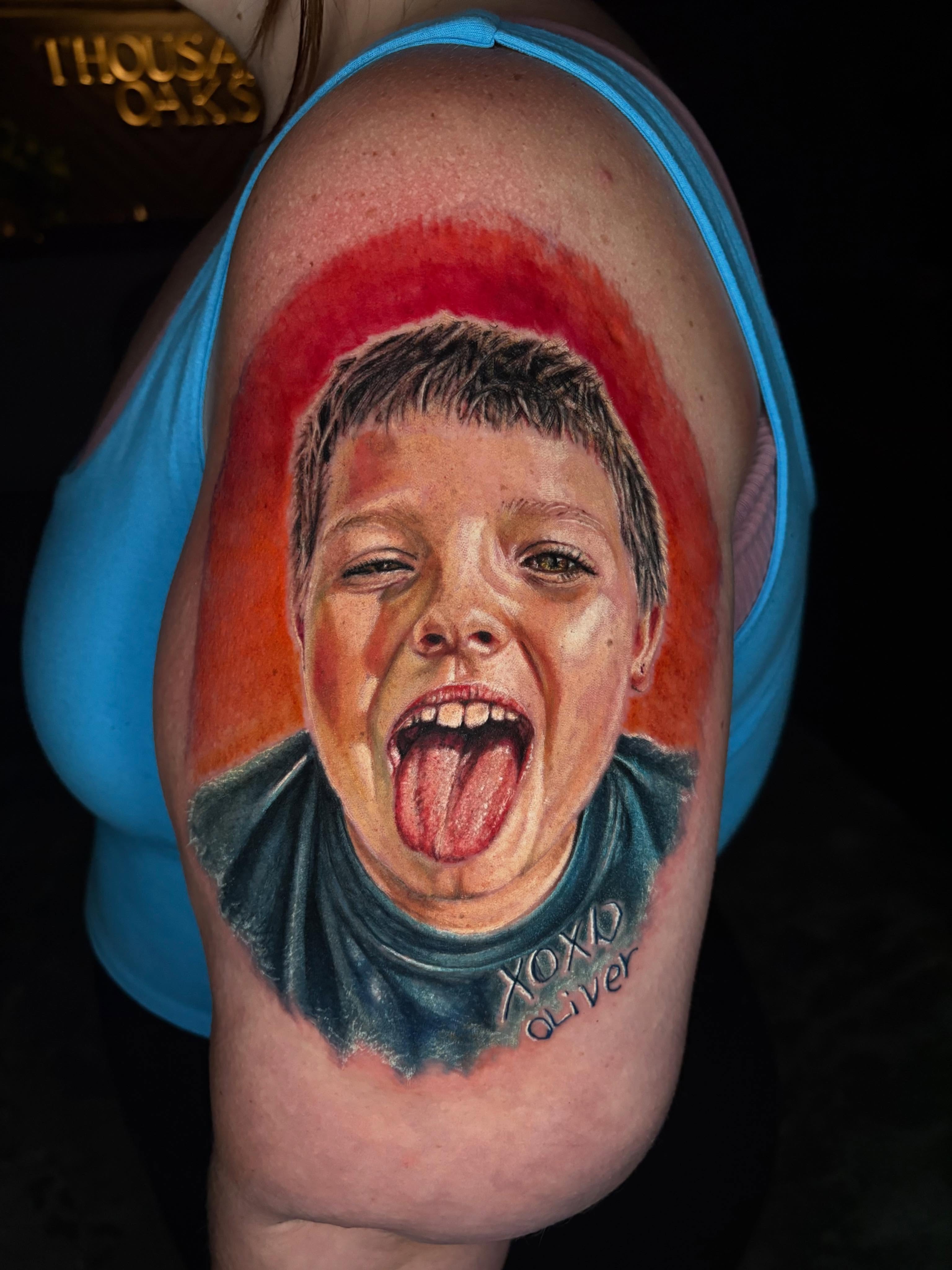 Child portrait with tongue out neo-traditional tattoo on the shoulder by Jacee Hamilton