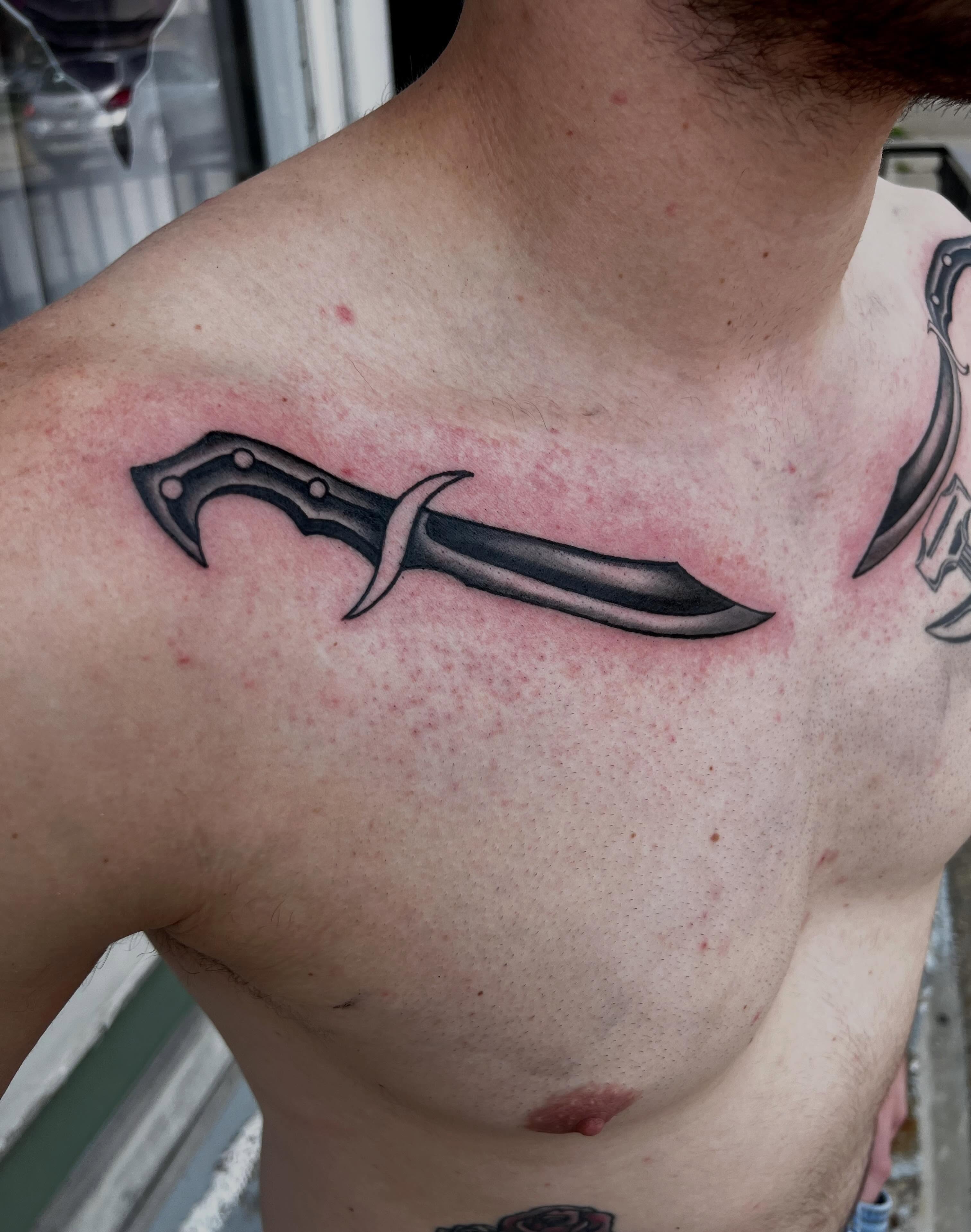 Knife black and grey tattoo on the chest by Ady Paige