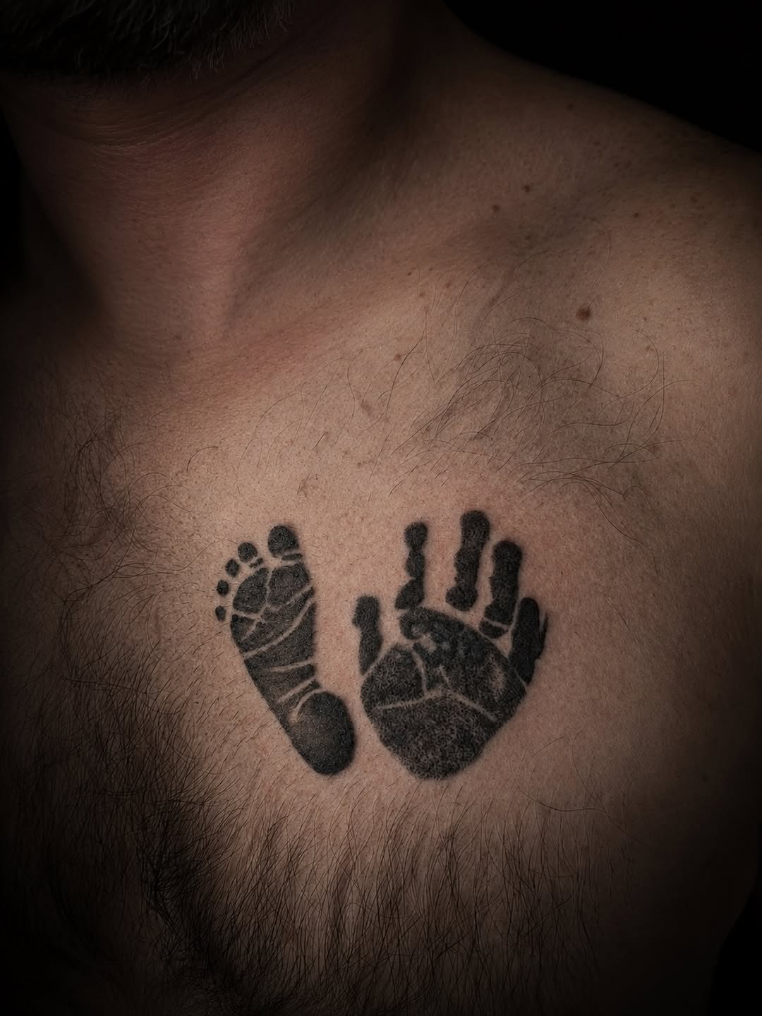 Baby footprint and handprint realism tattoo on the chest by 𝚃𝙰𝚃𝚃𝙾𝙾 𝙰𝚁𝚃𝙸𝚂𝚃, Charlotte, North Carolina