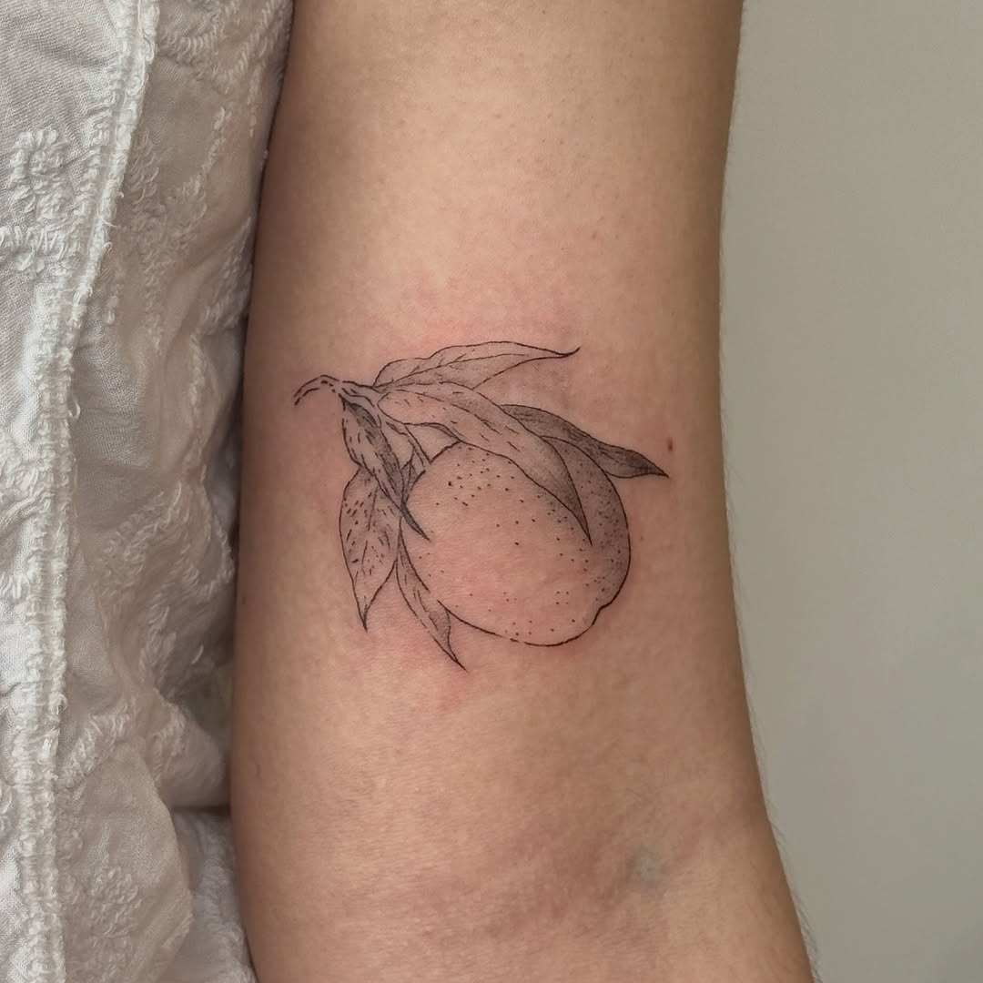 Orange with leaves minimalist tattoo on the forearm by Kirsten