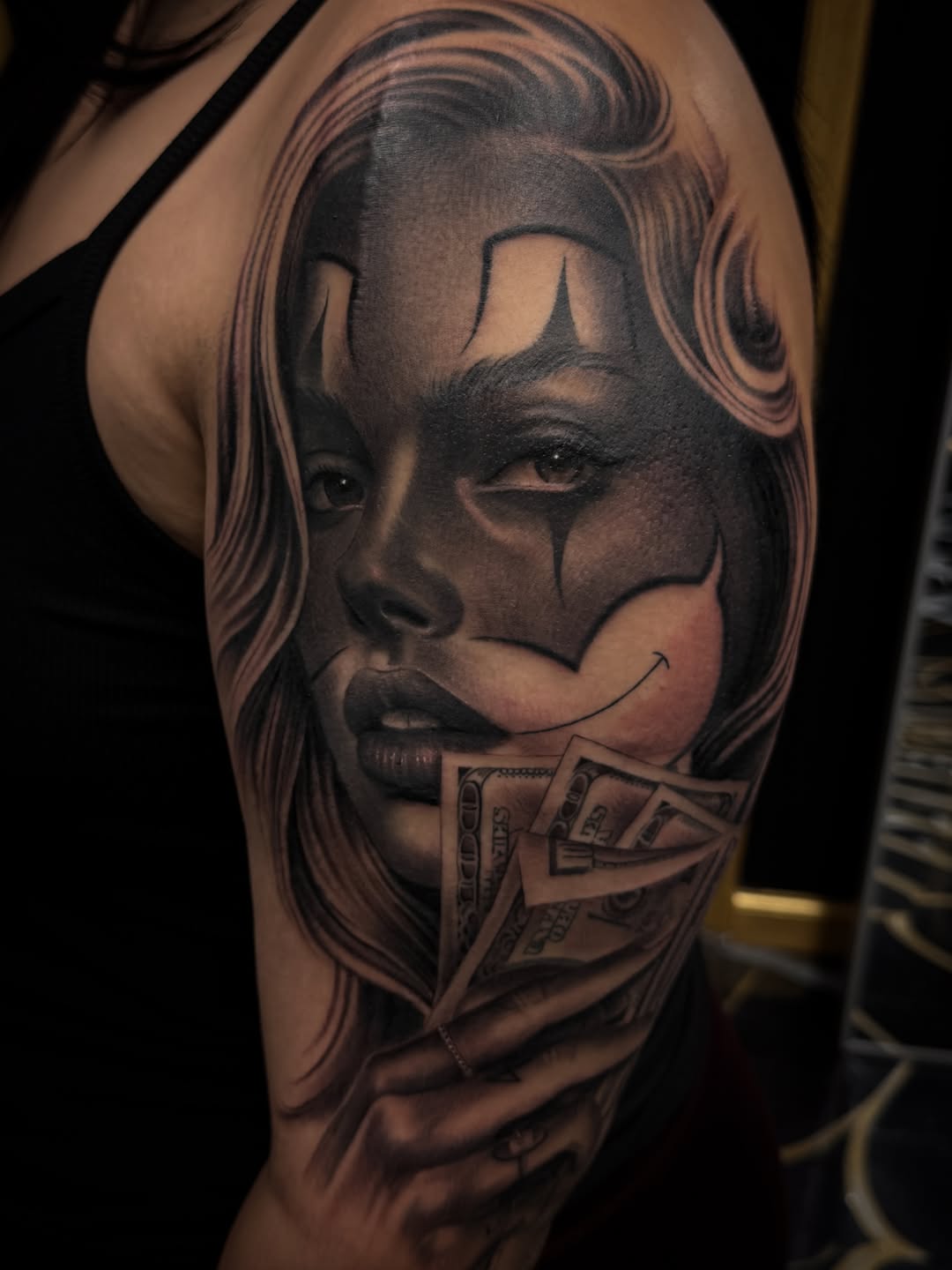 Woman with clown makeup and money Chicano tattoo on the shoulder by Gee Lagunas 🇲🇽, Springfield, Virginia