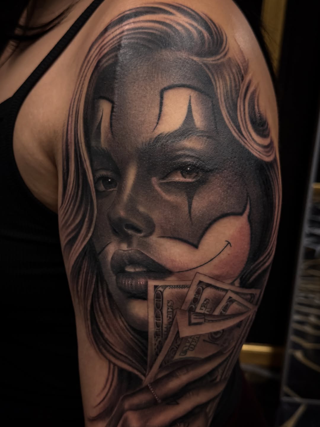 Woman with clown makeup and money Chicano tattoo on the upper arm by Gee Lagunas 🇲🇽, Springfield, Virginia