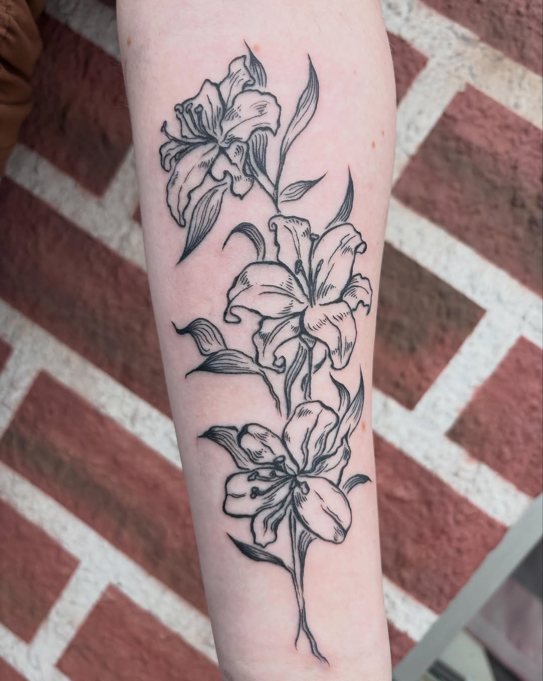 Lilies fine line tattoo on the forearm by izzy solae