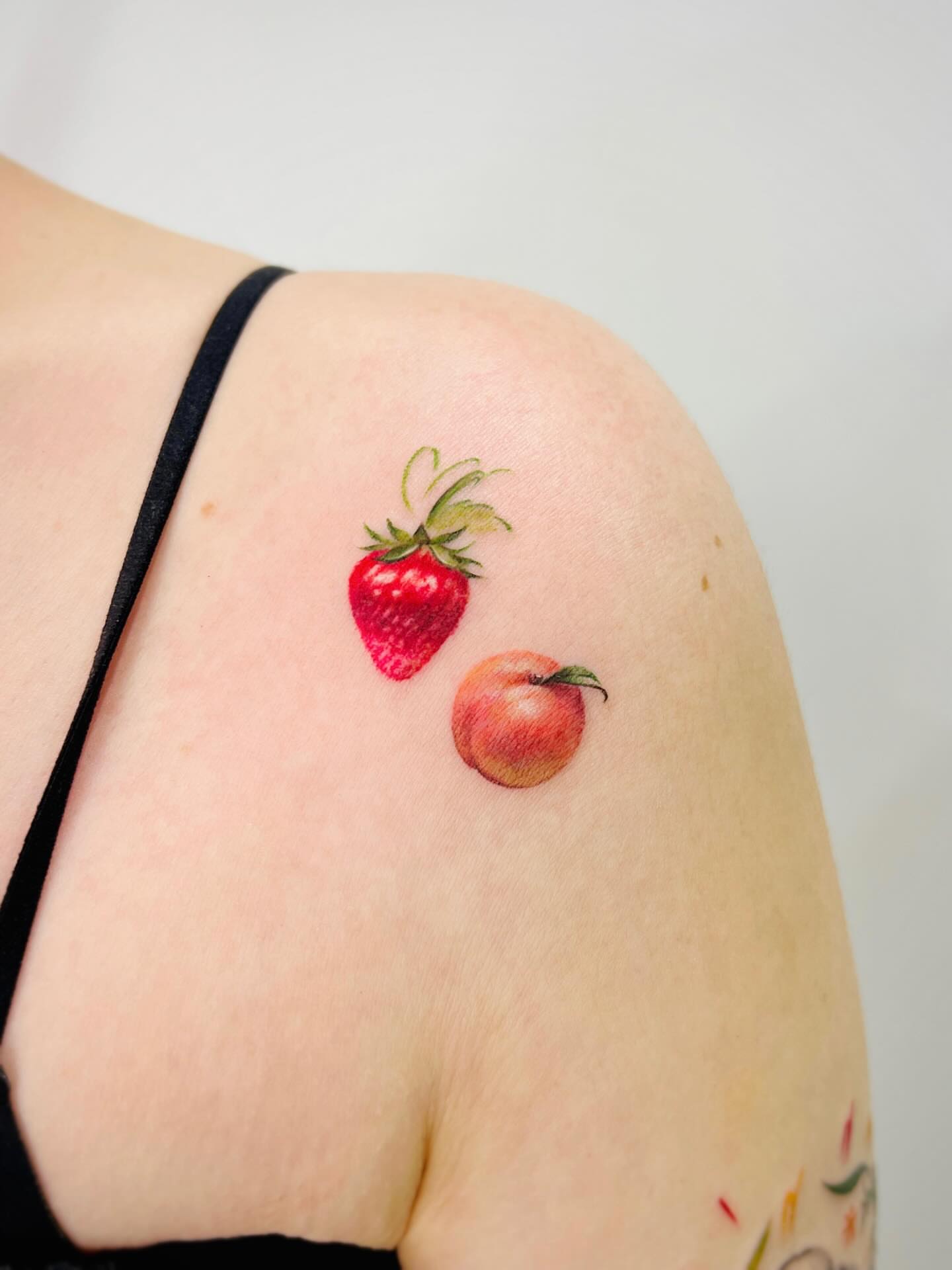 Strawberry and peach realism tattoo on the shoulder by Purinn