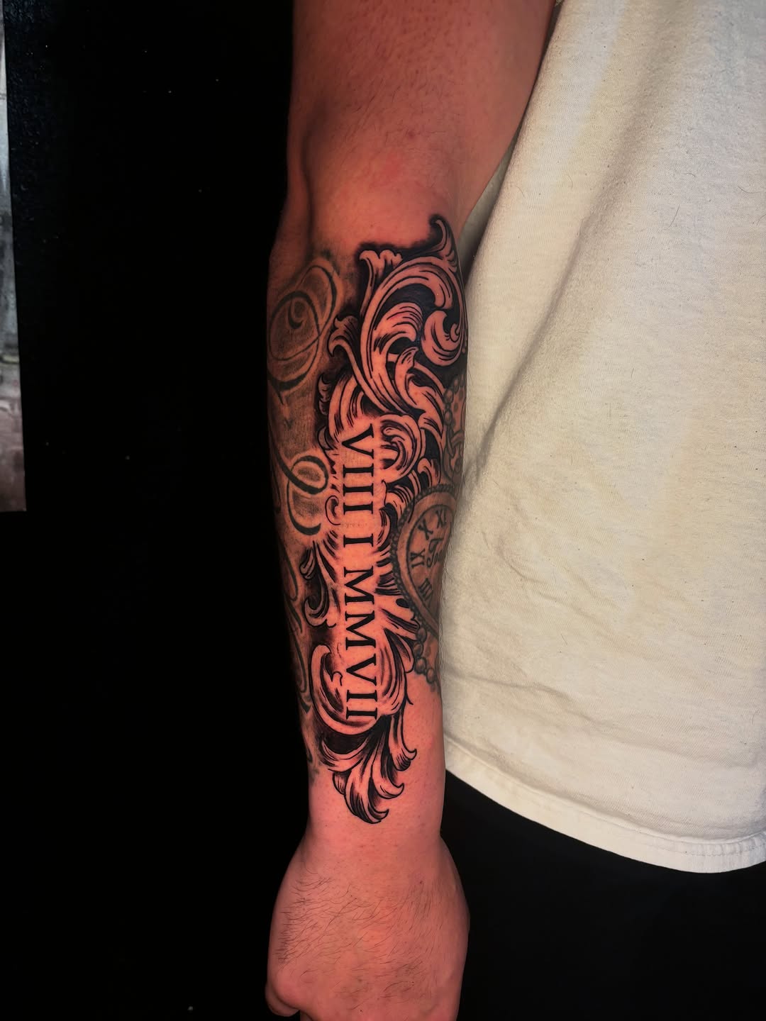 Ornamental scrollwork with roman numerals Chicano tattoo on the forearm by JT.tattoos