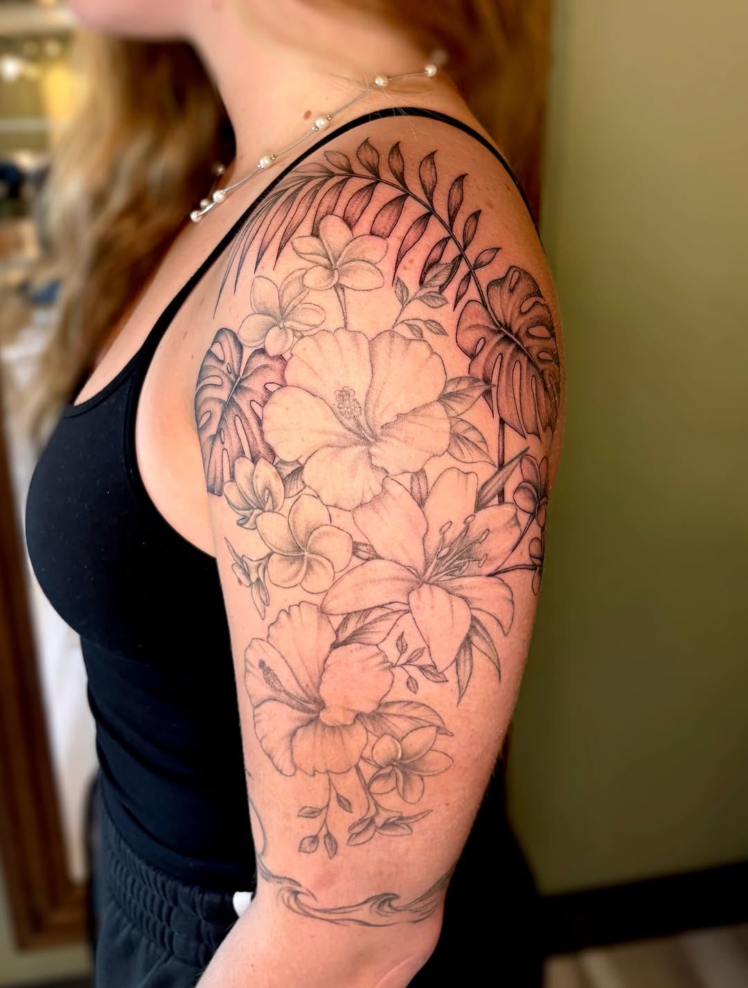 Tropical flowers and leaves fine line tattoo on the shoulder by Bianca Cattapan