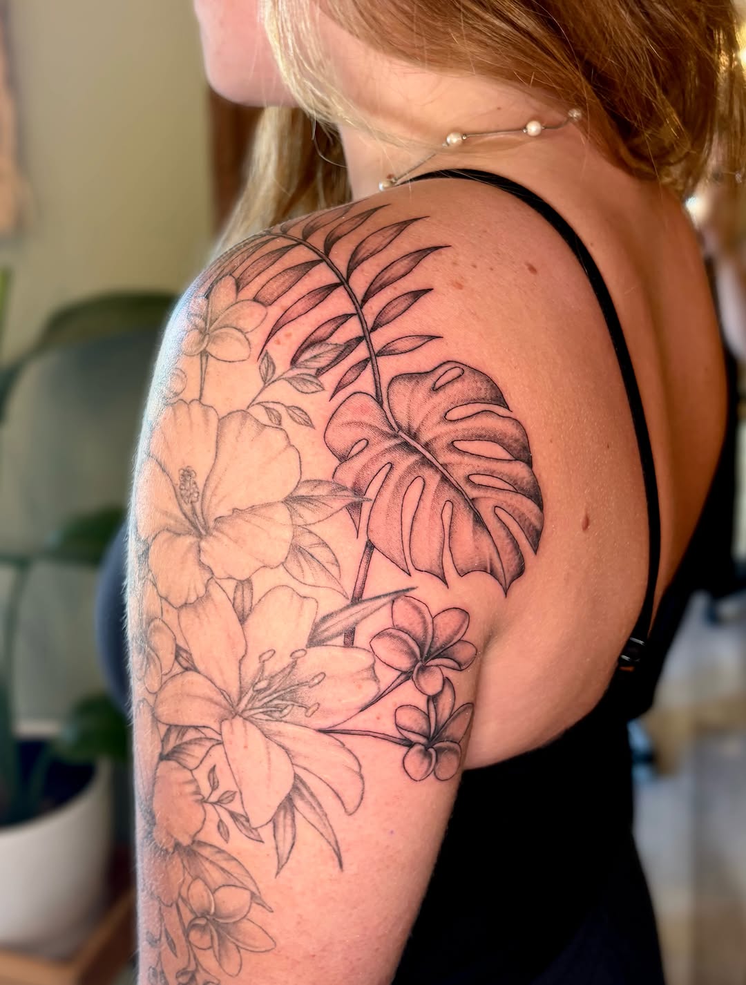 Tropical flowers and leaves fine line tattoo on the shoulder by Bianca Cattapan