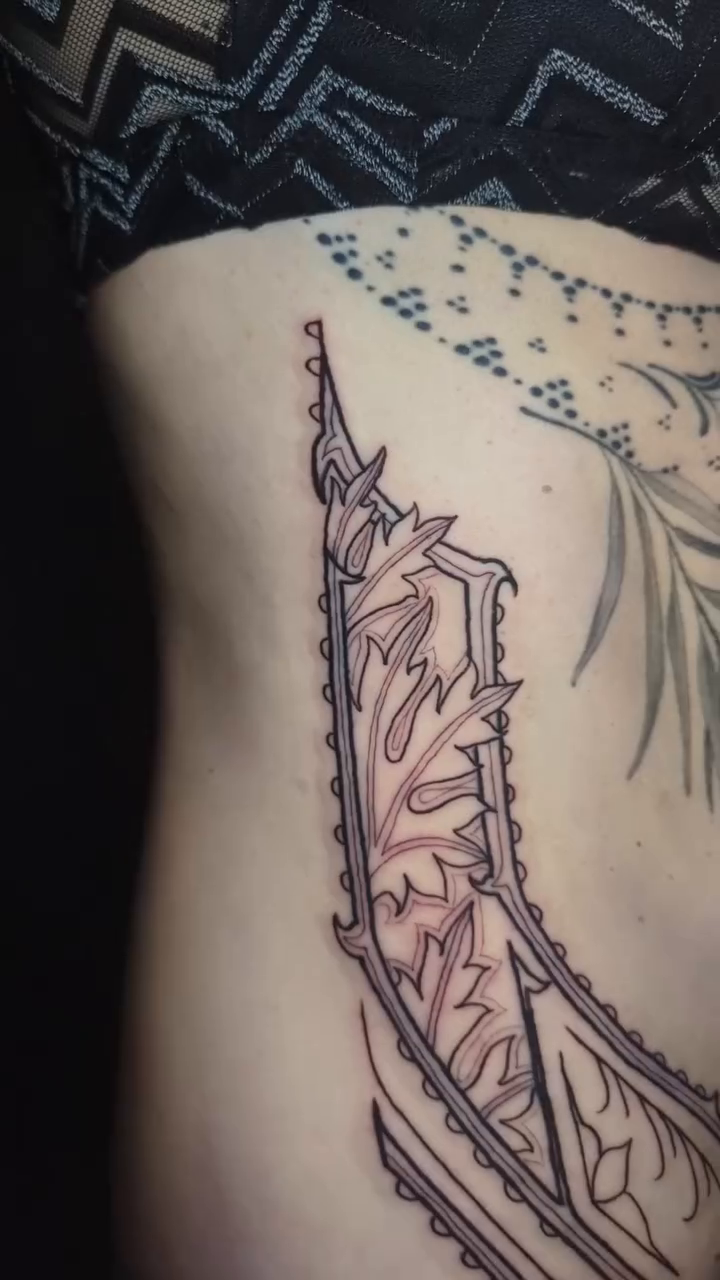 Feather with intricate patterns tribal tattoo on the back by Narnia Gallagher