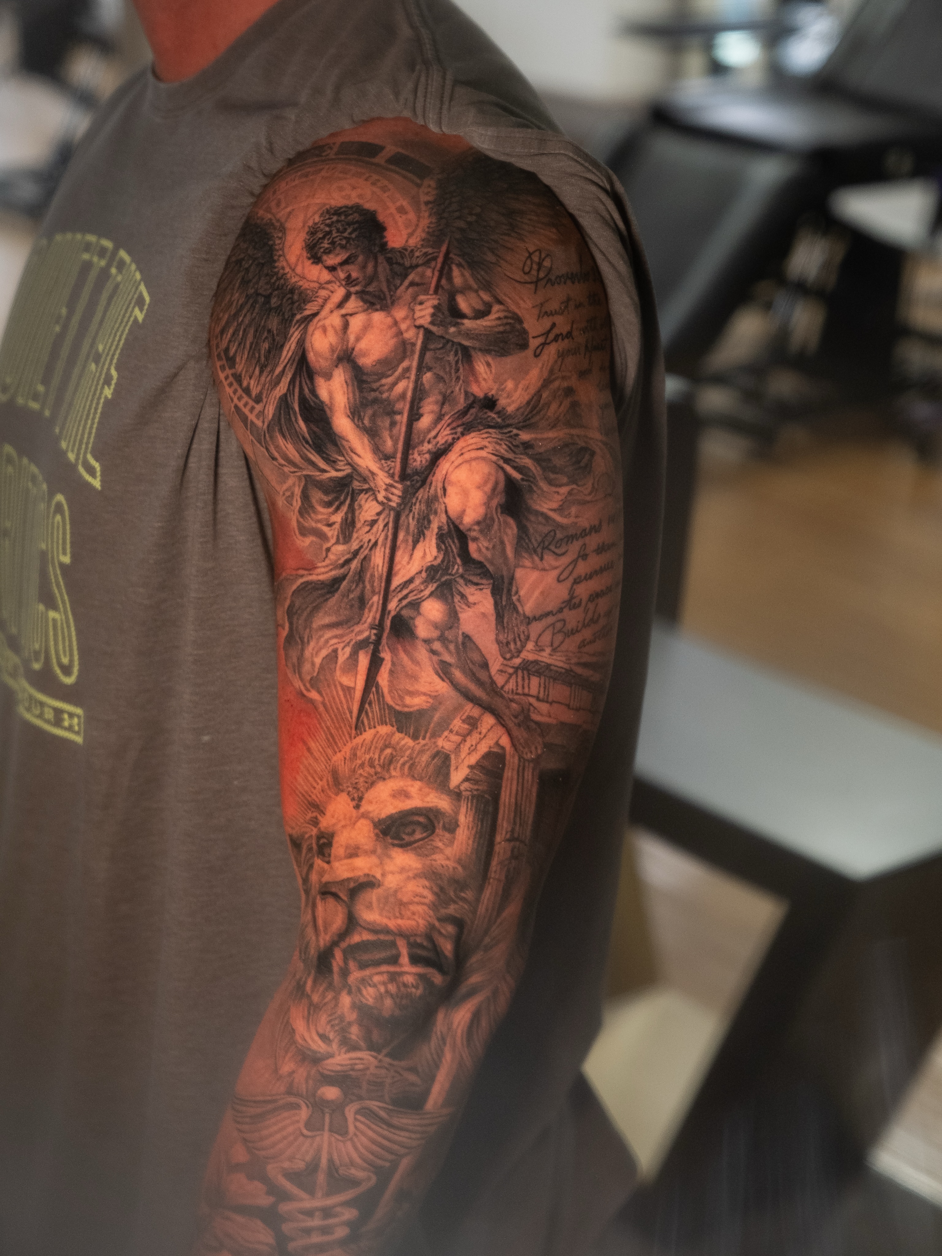 Angel and lion with scripture realism tattoo on the upper arm by Christopher Powell