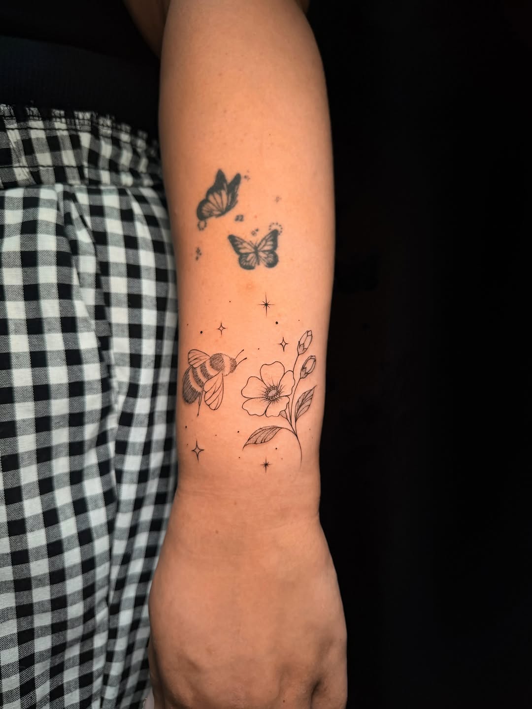 Bee and butterflies with flowers fine line tattoo on the forearm by Frida Tattooista