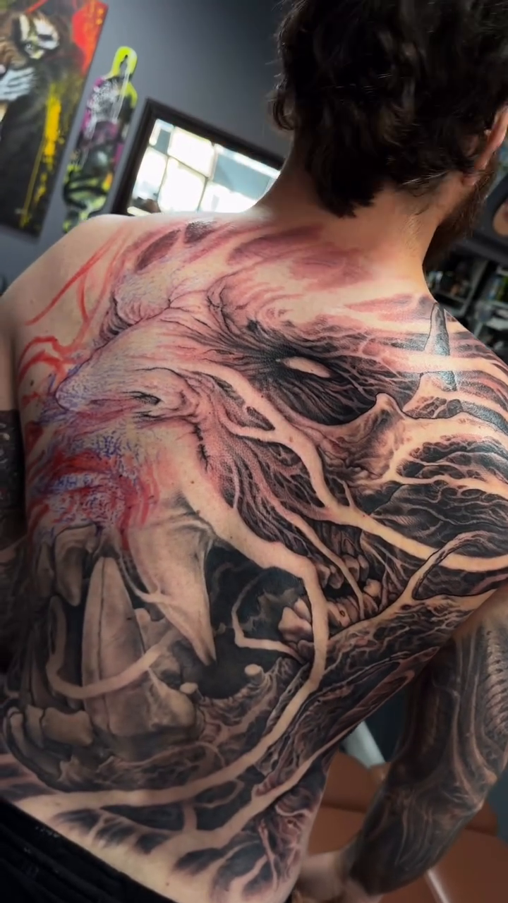 Demonic face and abstract elements dark art tattoo on the back by Nico Perez