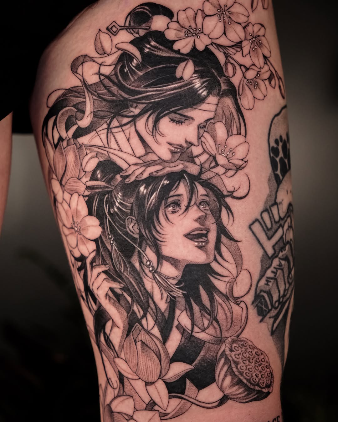 Two anime-style figures with flowers anime tattoo on the thigh by Hemi 혜미타투