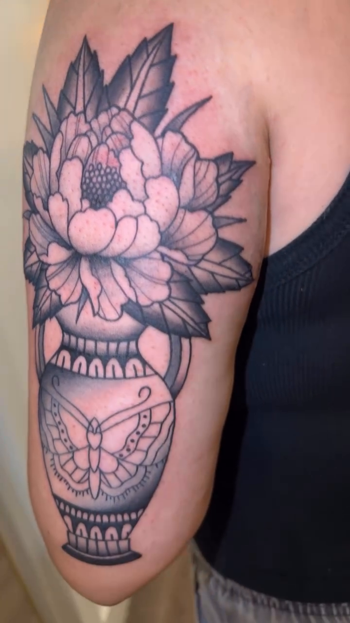 Vase with flowers and butterflies dotwork tattoo on the upper arm by Natalie